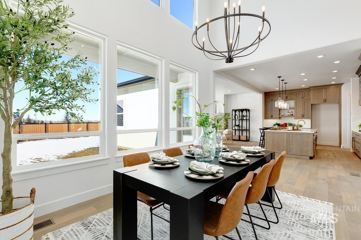 Dining space with recessed lighting, light wood-type flooring, a chandelier, and a towering ceiling