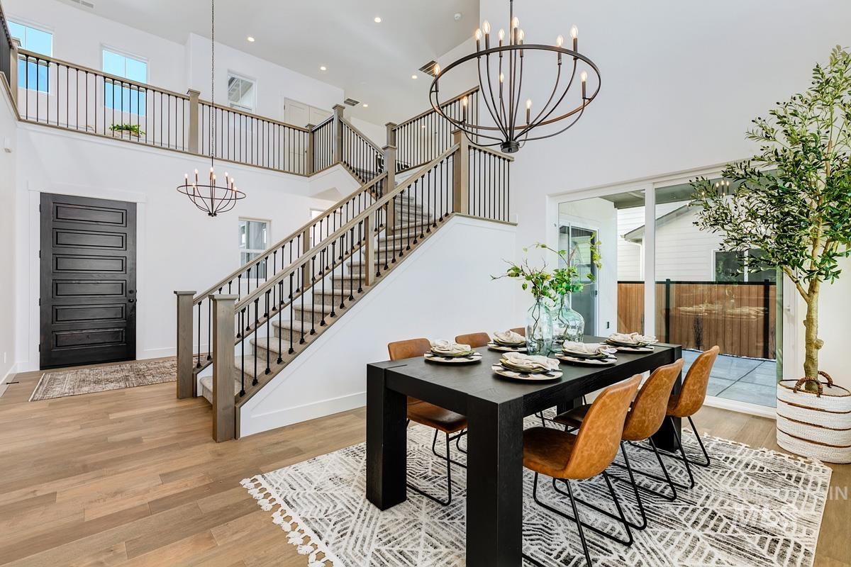 Dining space with a chandelier, a high ceiling, light wood-style flooring, recessed lighting, and stairway