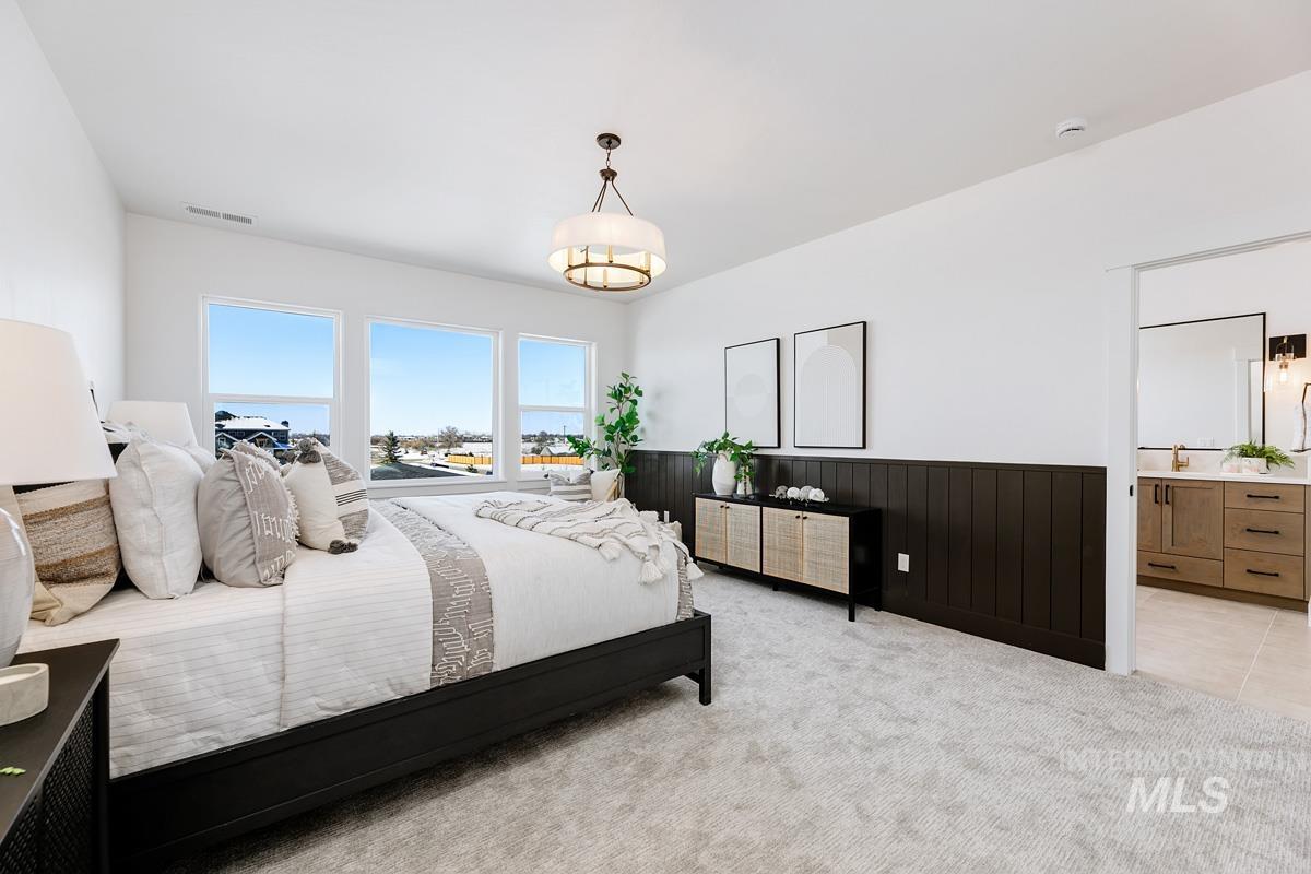 Bedroom featuring light carpet, wainscoting, wood walls, and connected bathroom