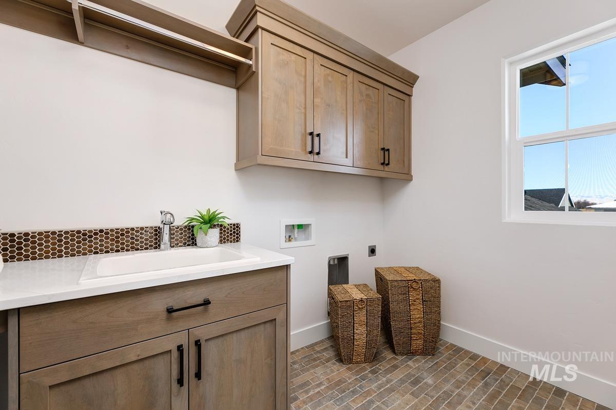 Washroom with brick floors, hookup for a washing machine, cabinet space, and hookup for an electric dryer