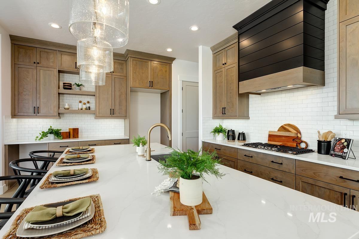Kitchen featuring custom range hood, recessed lighting, brown cabinetry, light stone counters, and backsplash