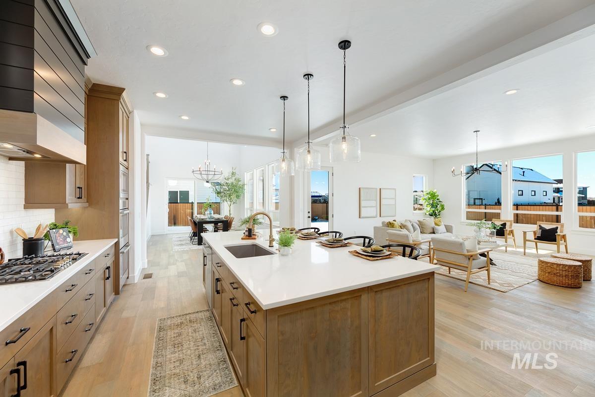 Kitchen with a chandelier, brown cabinetry, light wood-style flooring, hanging light fixtures, and recessed lighting