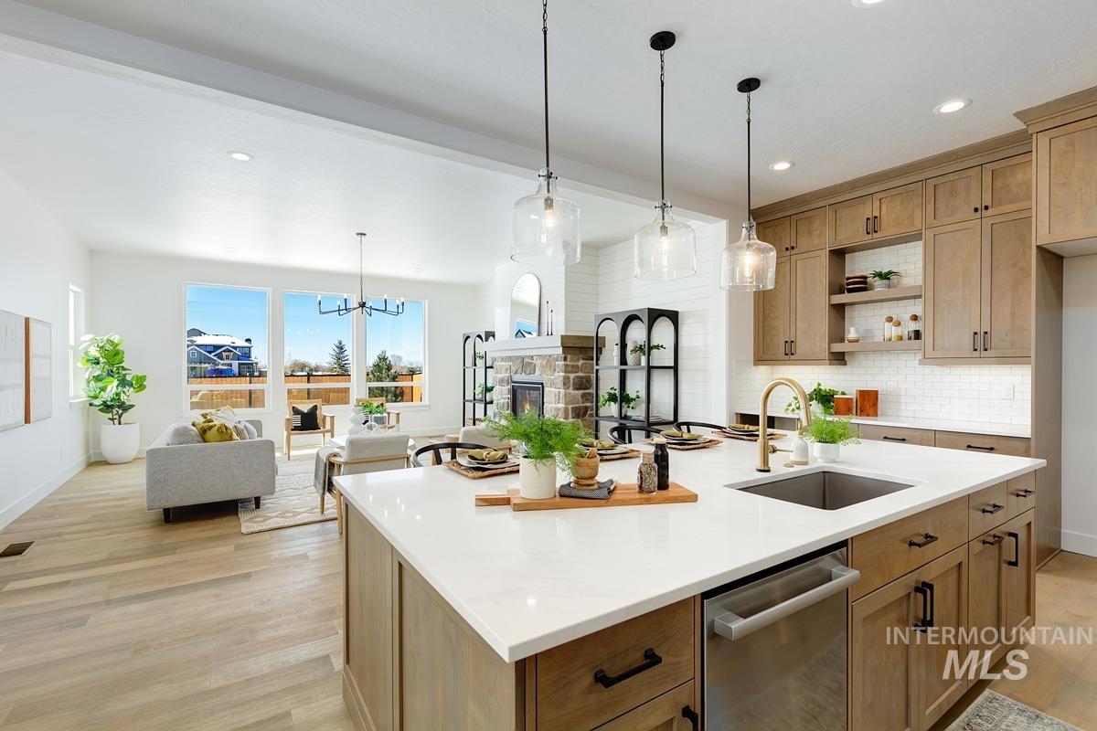 Kitchen featuring tasteful backsplash, pendant lighting, dishwasher, open floor plan, and light wood finished floors