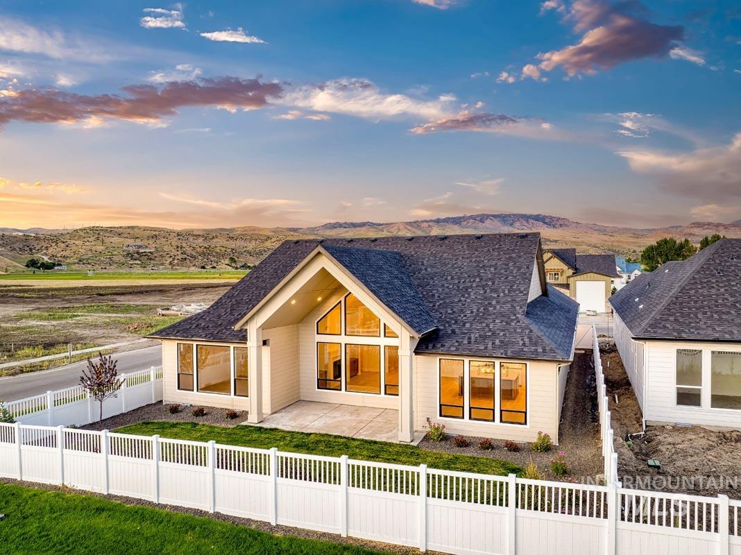Back of house at dusk with a fenced backyard, a shingled roof, a mountain view, and a patio area