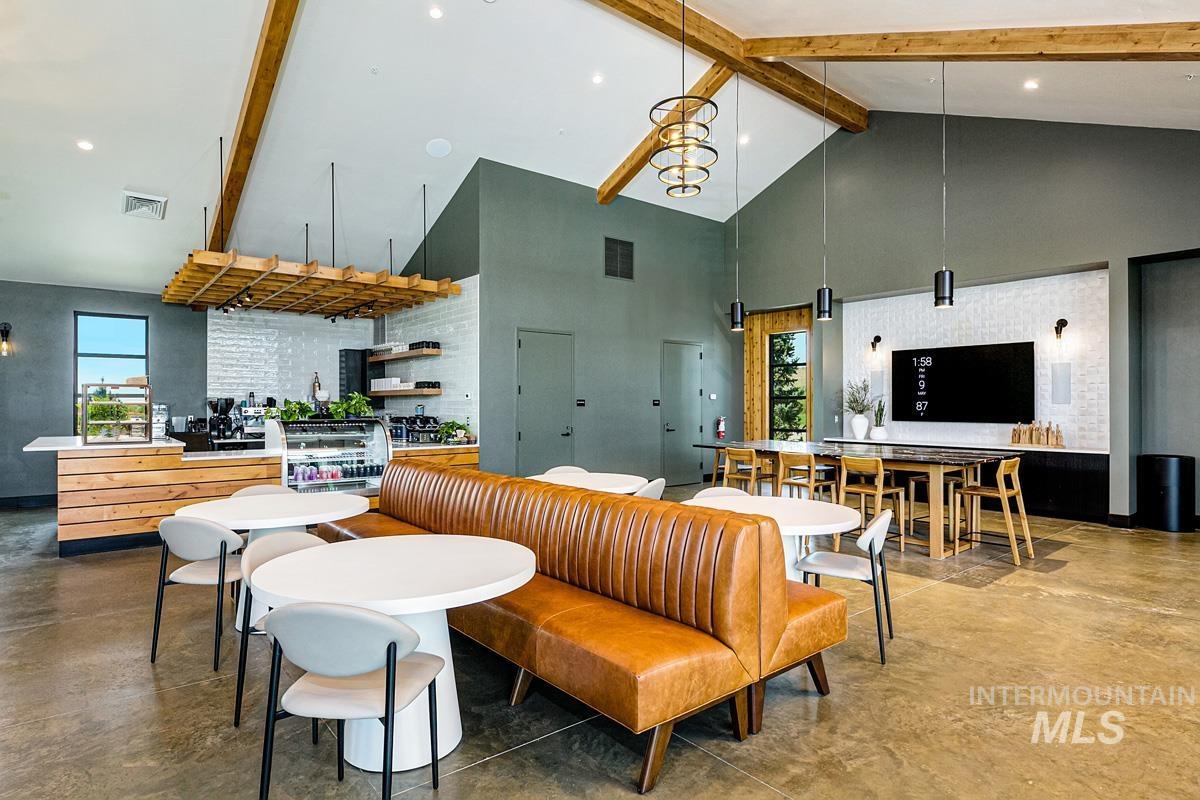 Living area with beam ceiling, concrete flooring, high vaulted ceiling, plenty of natural light, and a chandelier