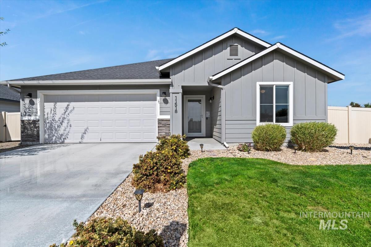 Ranch-style home with board and batten siding, concrete driveway, a garage, stone siding, and roof with shingles