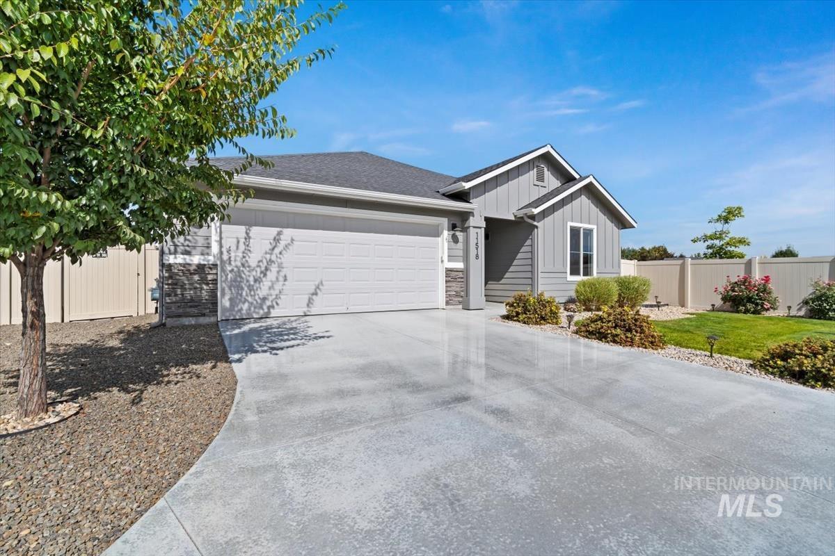 Ranch-style house featuring board and batten siding, concrete driveway, an attached garage, roof with shingles, and stone siding