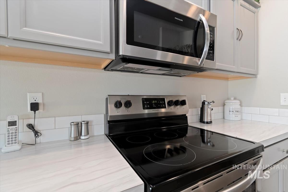 Kitchen with stainless steel appliances, light countertops, and white cabinets