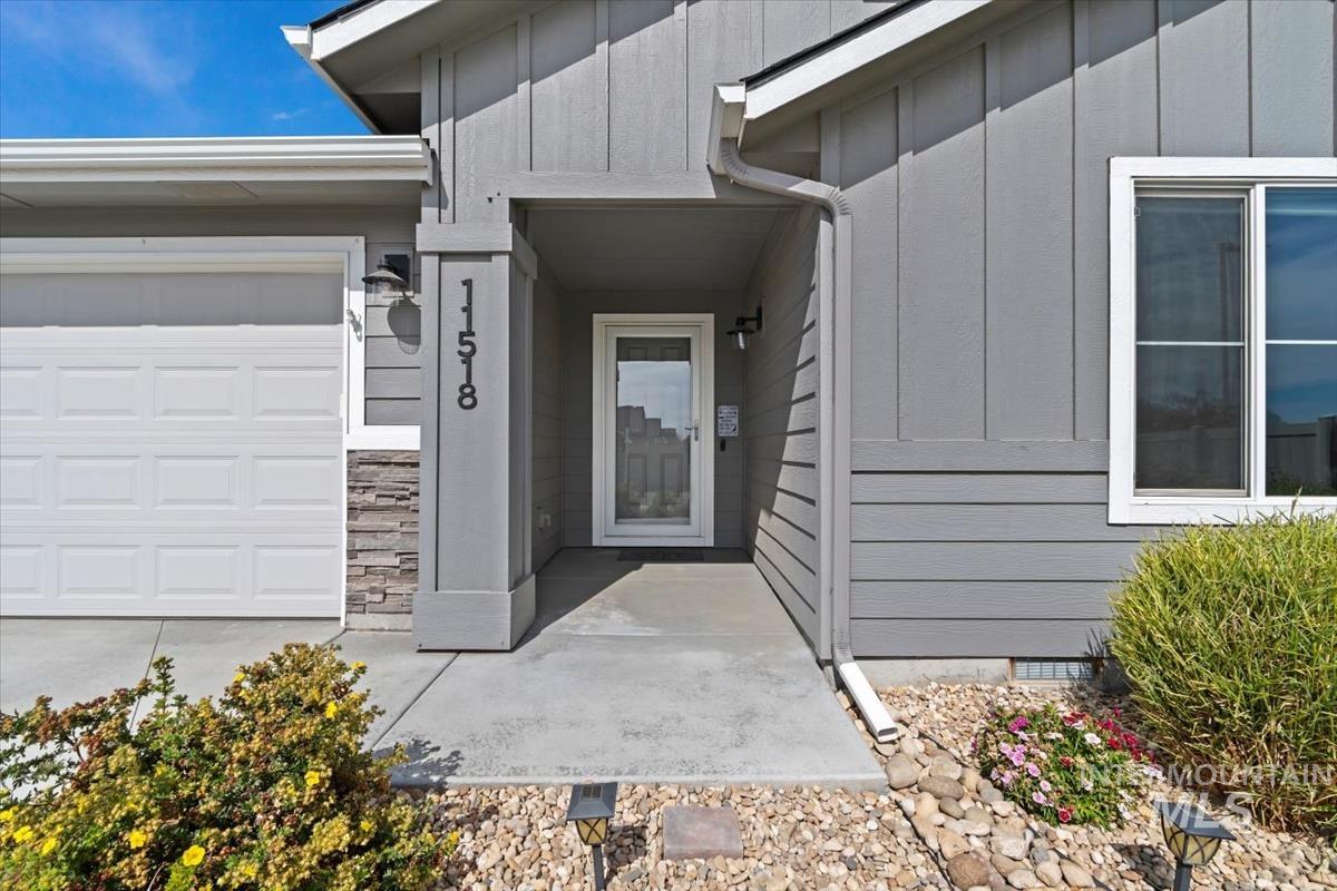 Property entrance with board and batten siding, stone siding, and a garage