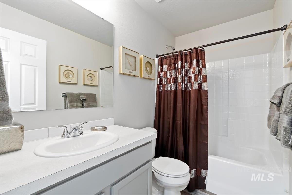 Bathroom featuring shower / bathtub combination with curtain and vanity