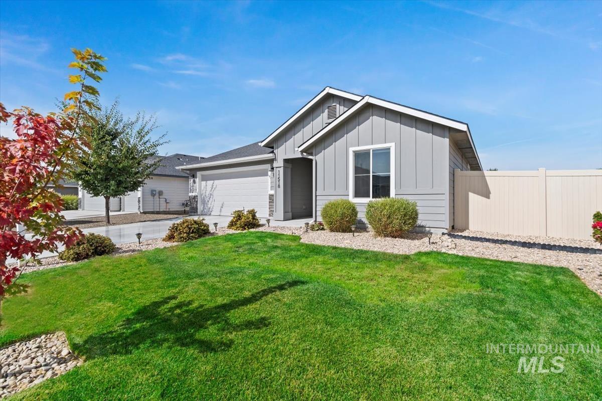 Single story home with board and batten siding, an attached garage, and driveway