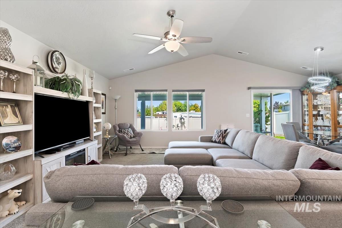 Carpeted living area featuring lofted ceiling and a ceiling fan