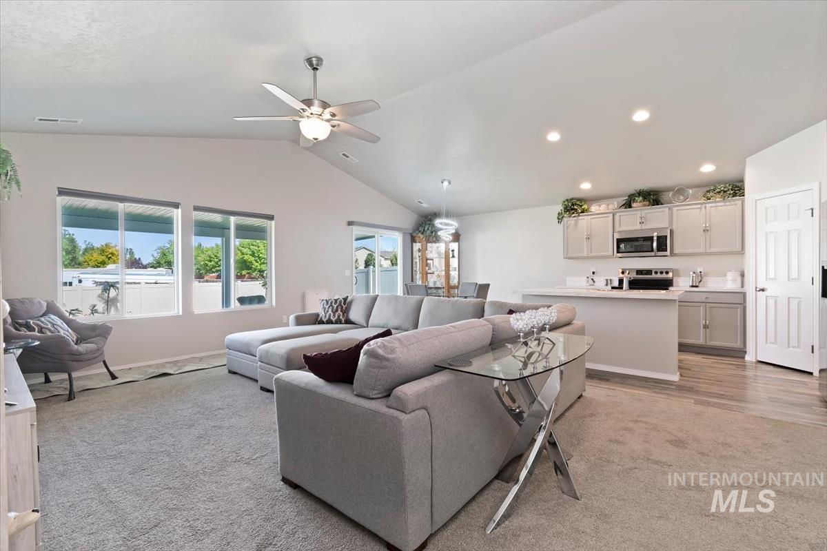 Living area featuring recessed lighting, vaulted ceiling, light carpet, and a ceiling fan