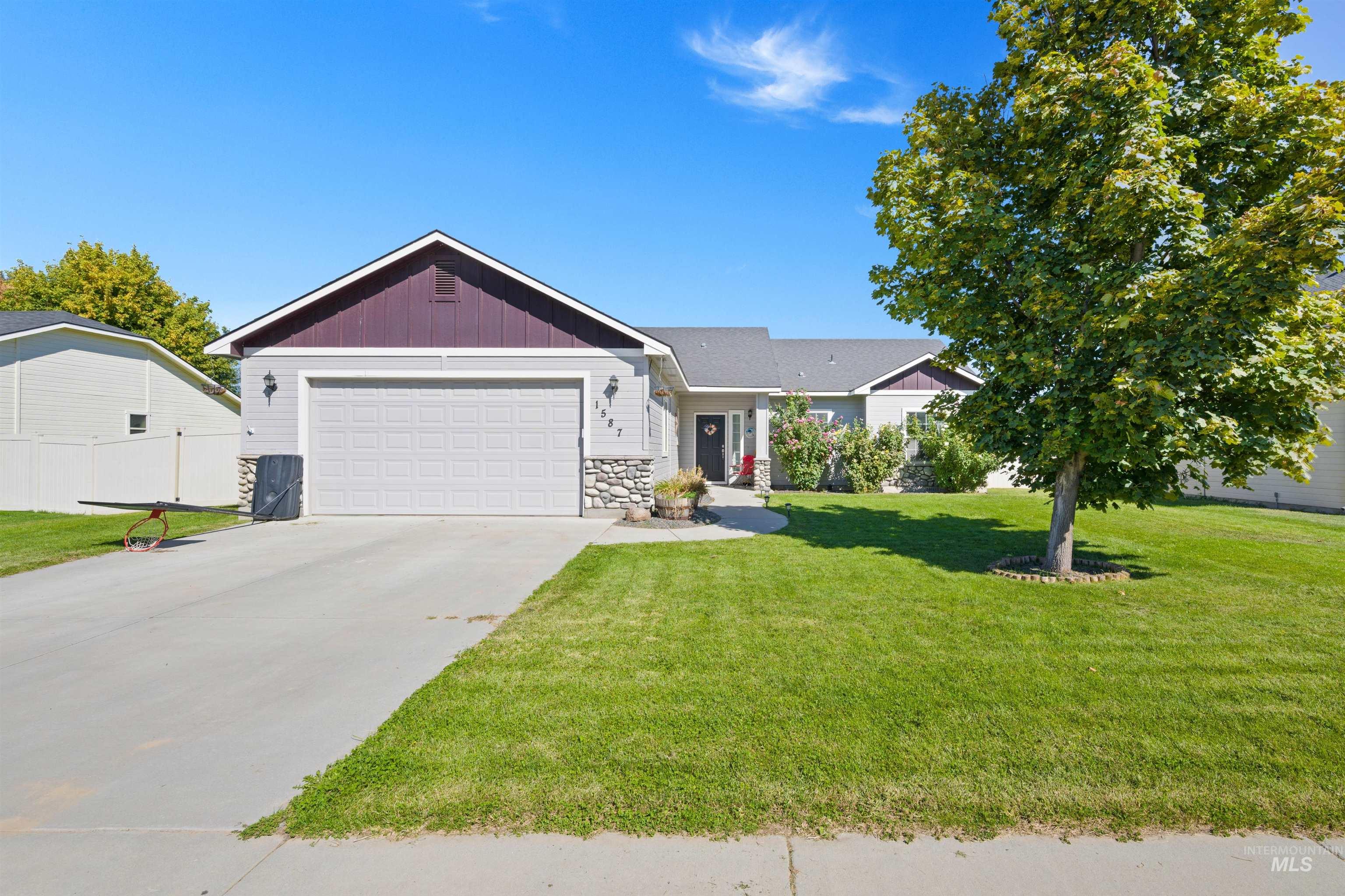 Ranch-style home with a front lawn, concrete driveway, stone siding, and a garage