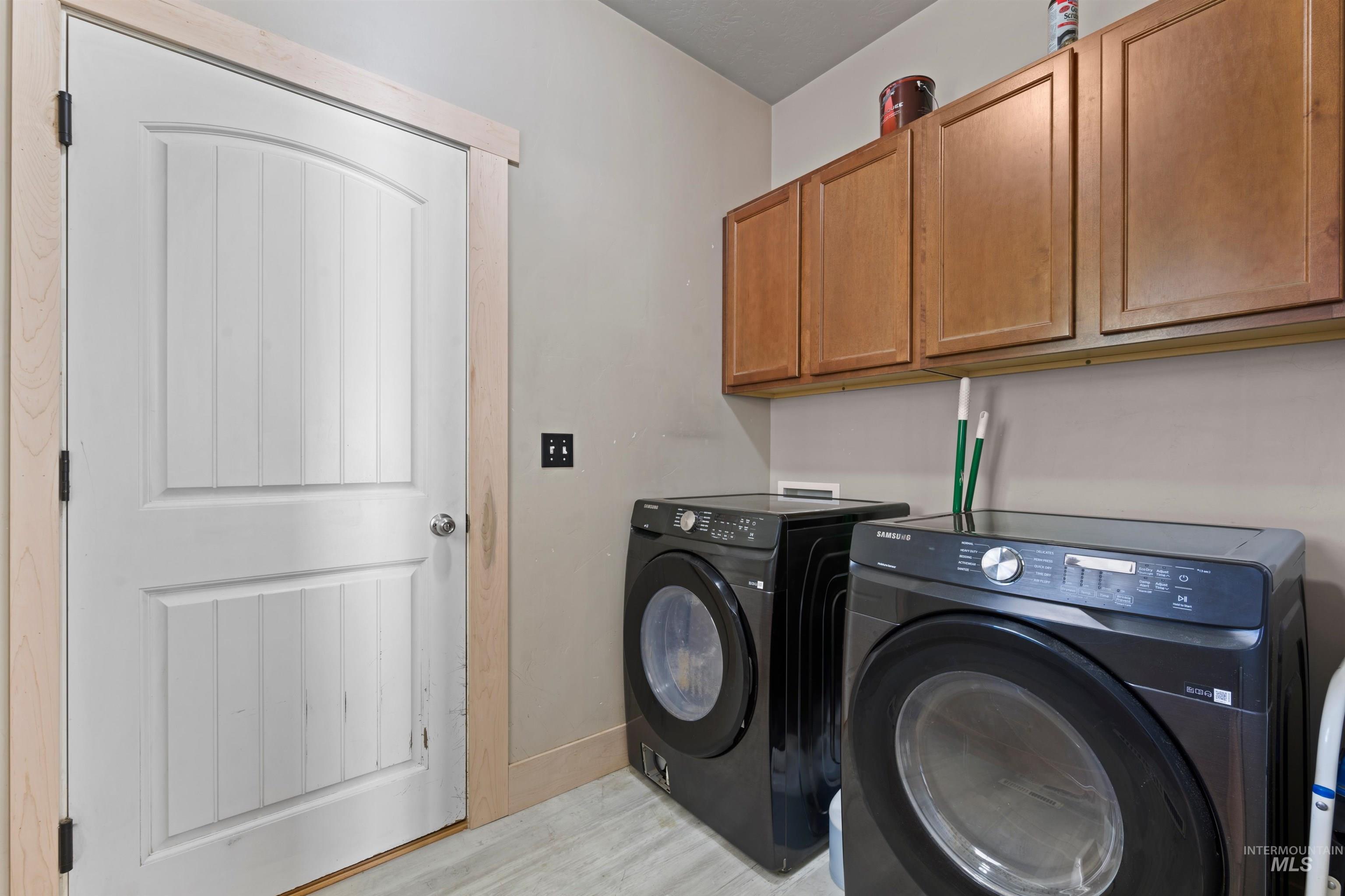 Washroom featuring cabinet space, washer and clothes dryer, and light wood finished floors