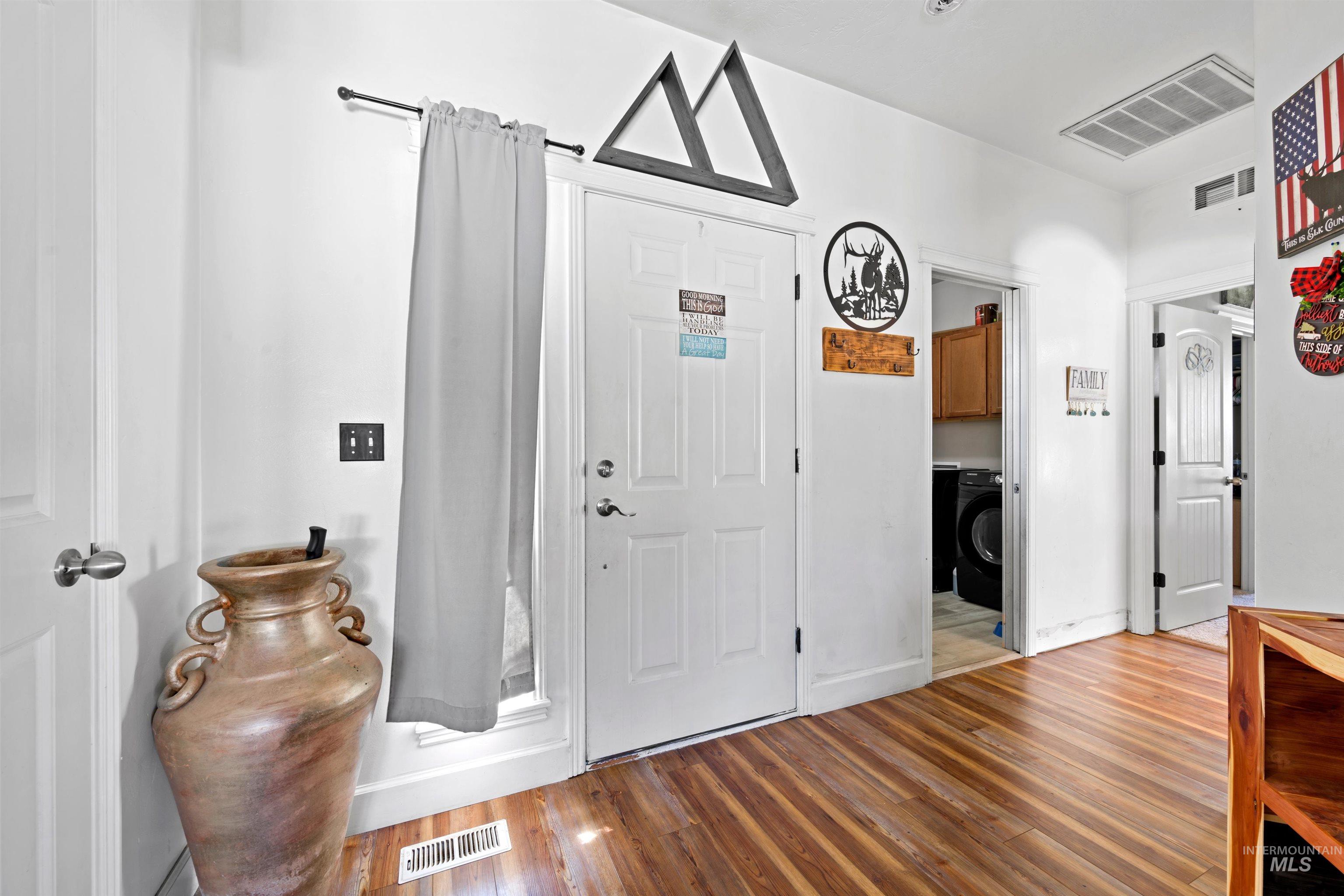 Foyer entrance with wood finished floors and washer / dryer