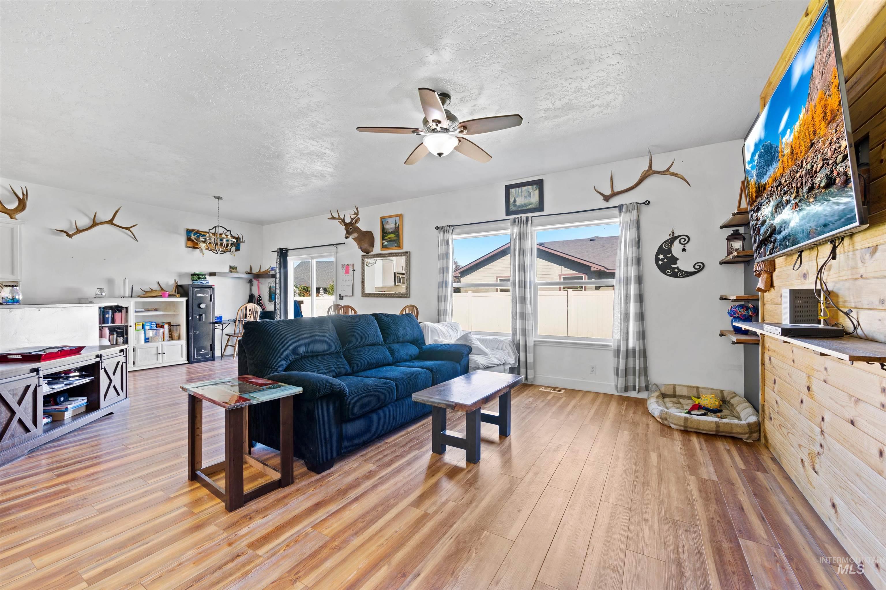 Living area with ceiling fan, light wood-style flooring, and a textured ceiling