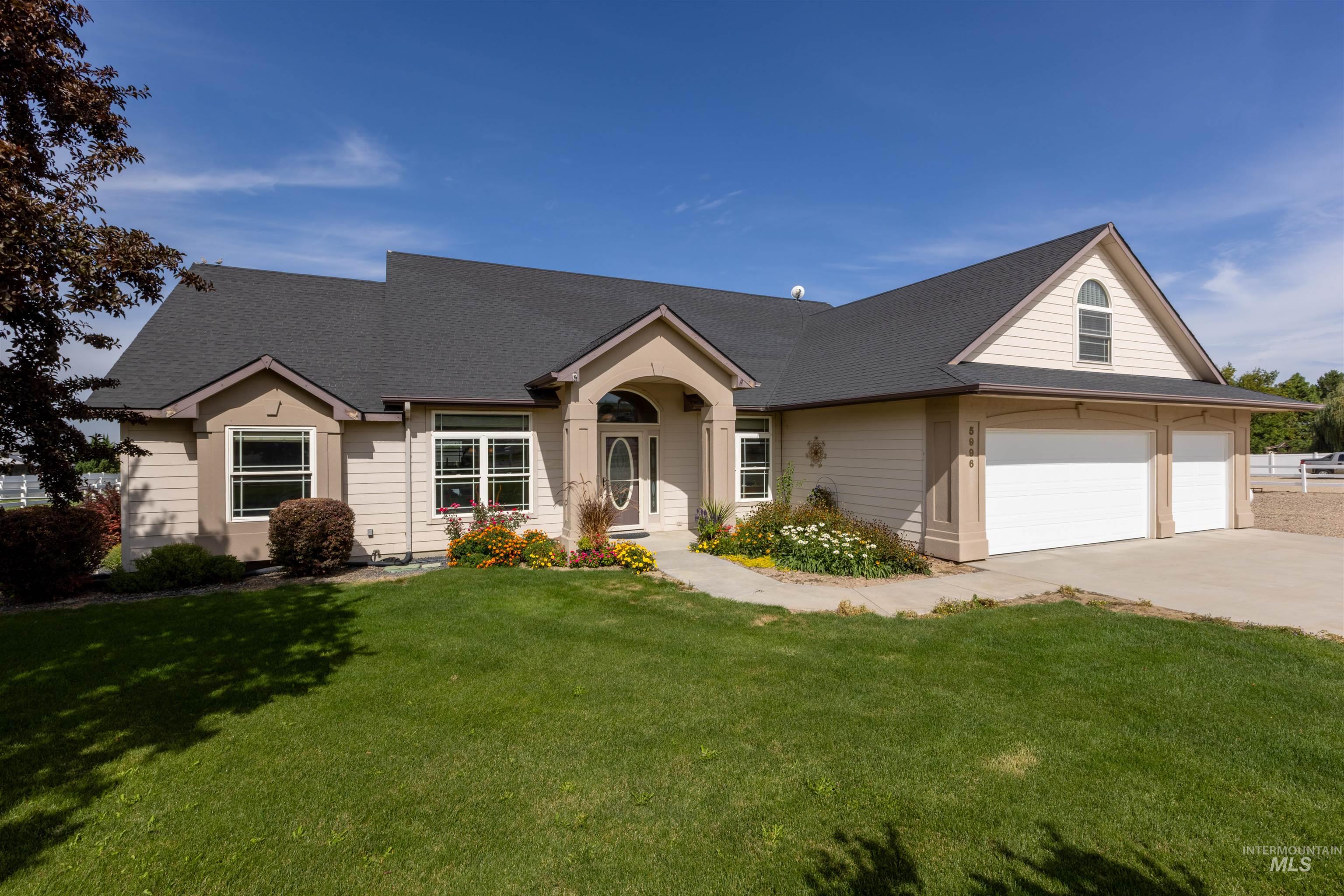 View of front of house with a shingled roof, a garage, a front yard, and driveway