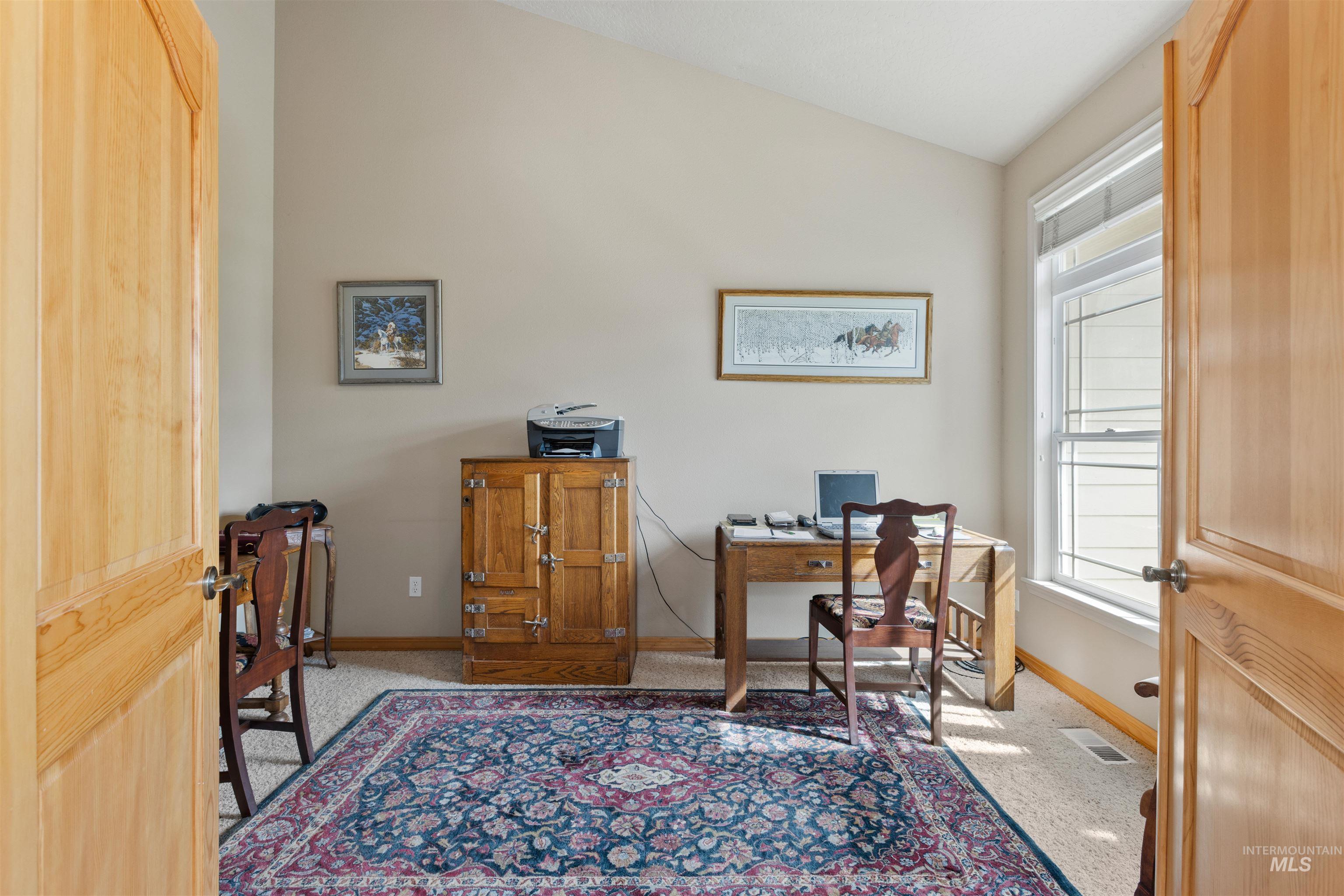 Carpeted home office with vaulted ceiling and baseboards