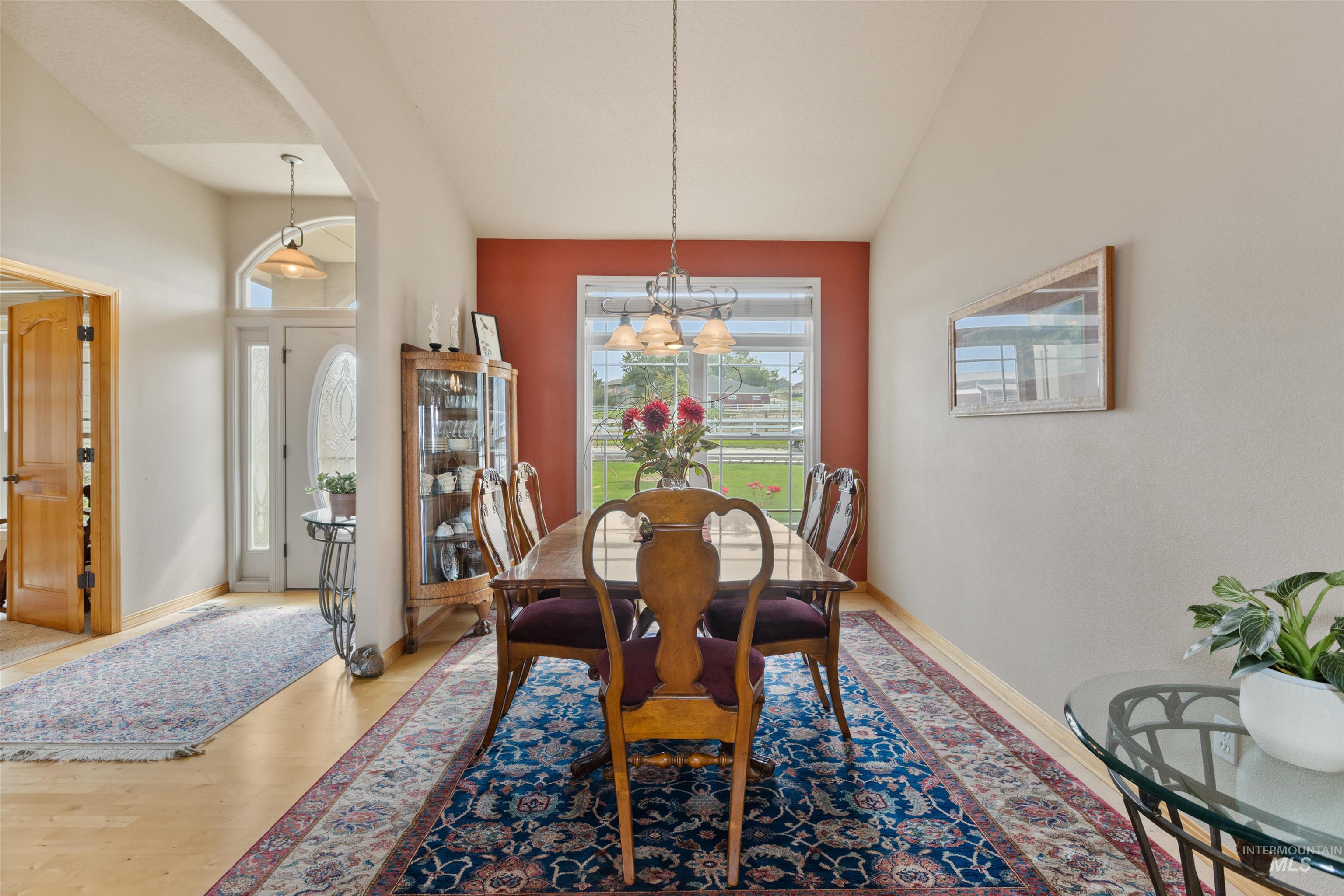 Dining space with arched walkways, wood finished floors, a chandelier, and high vaulted ceiling