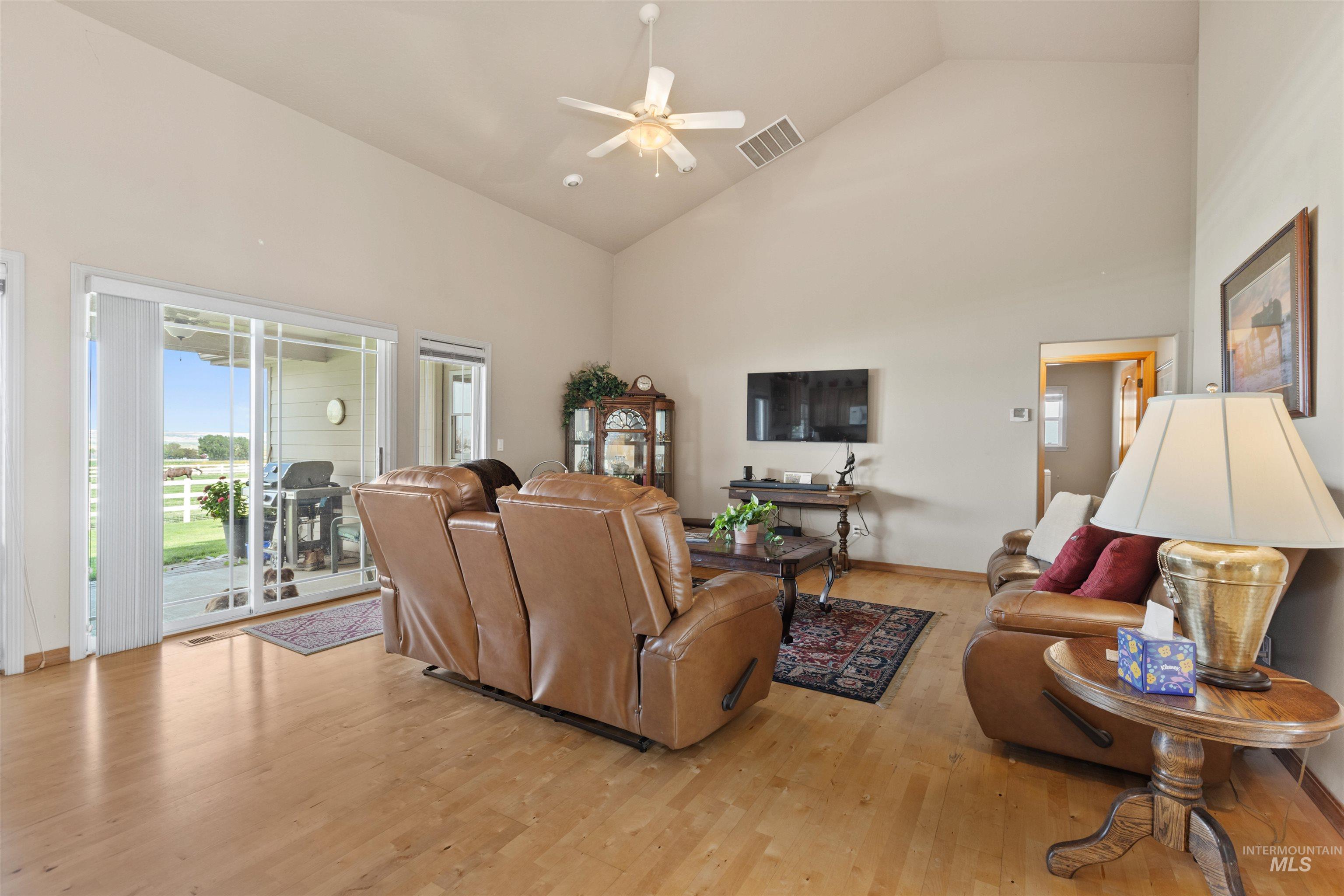 Living room with high vaulted ceiling, light wood-style floors, and a ceiling fan