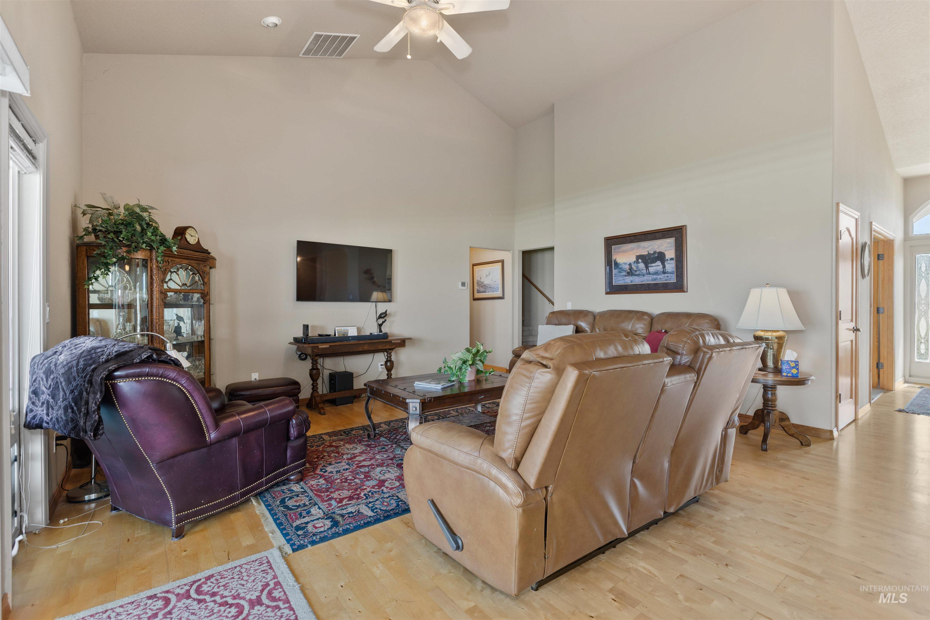 Living room featuring high vaulted ceiling, light wood-type flooring, and a ceiling fan