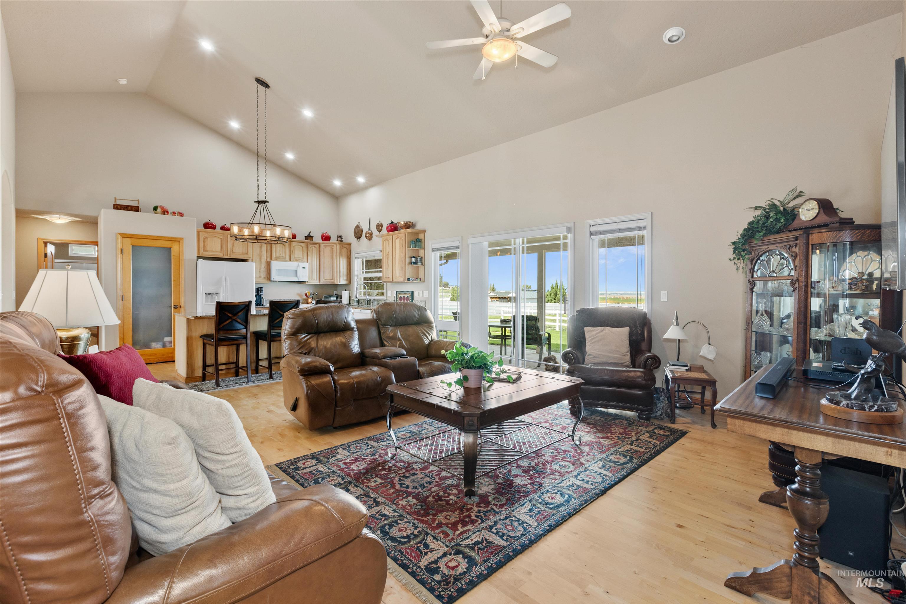 Living area featuring high vaulted ceiling, light wood-type flooring, recessed lighting, and a ceiling fan
