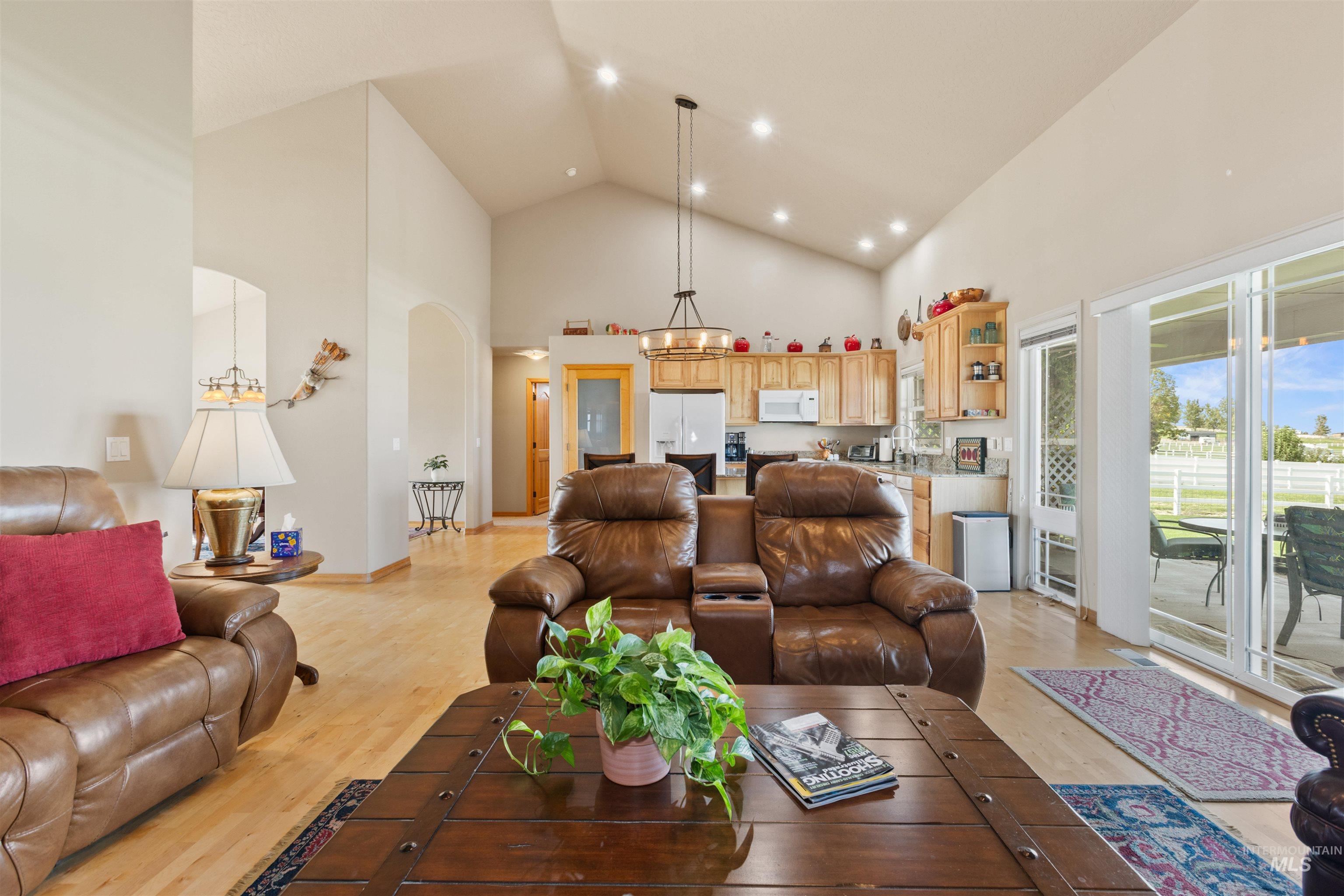 Living room featuring high vaulted ceiling, light wood-style floors, arched walkways, and recessed lighting