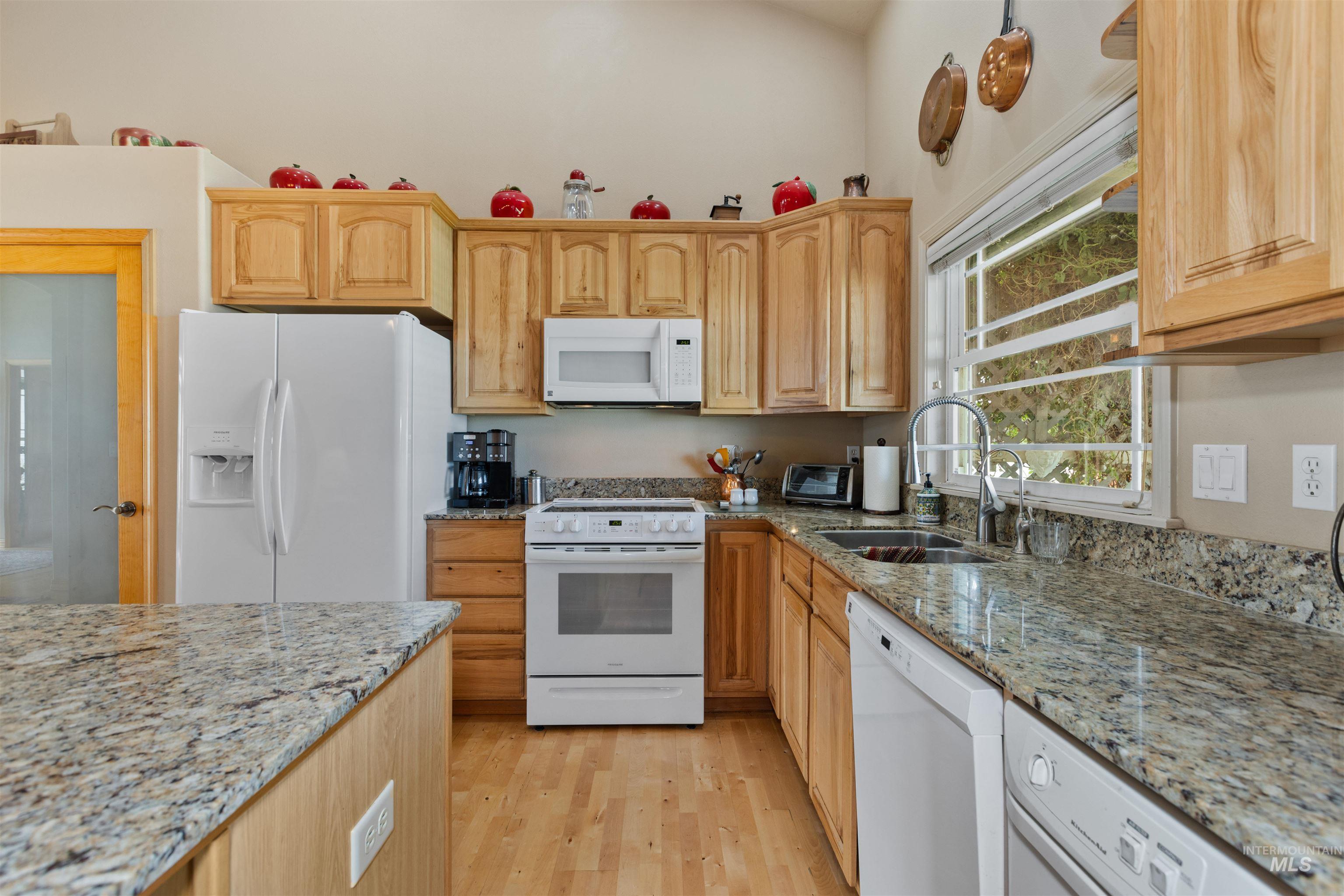 Kitchen featuring white appliances, light stone counters, light wood-style flooring, and light brown cabinetry