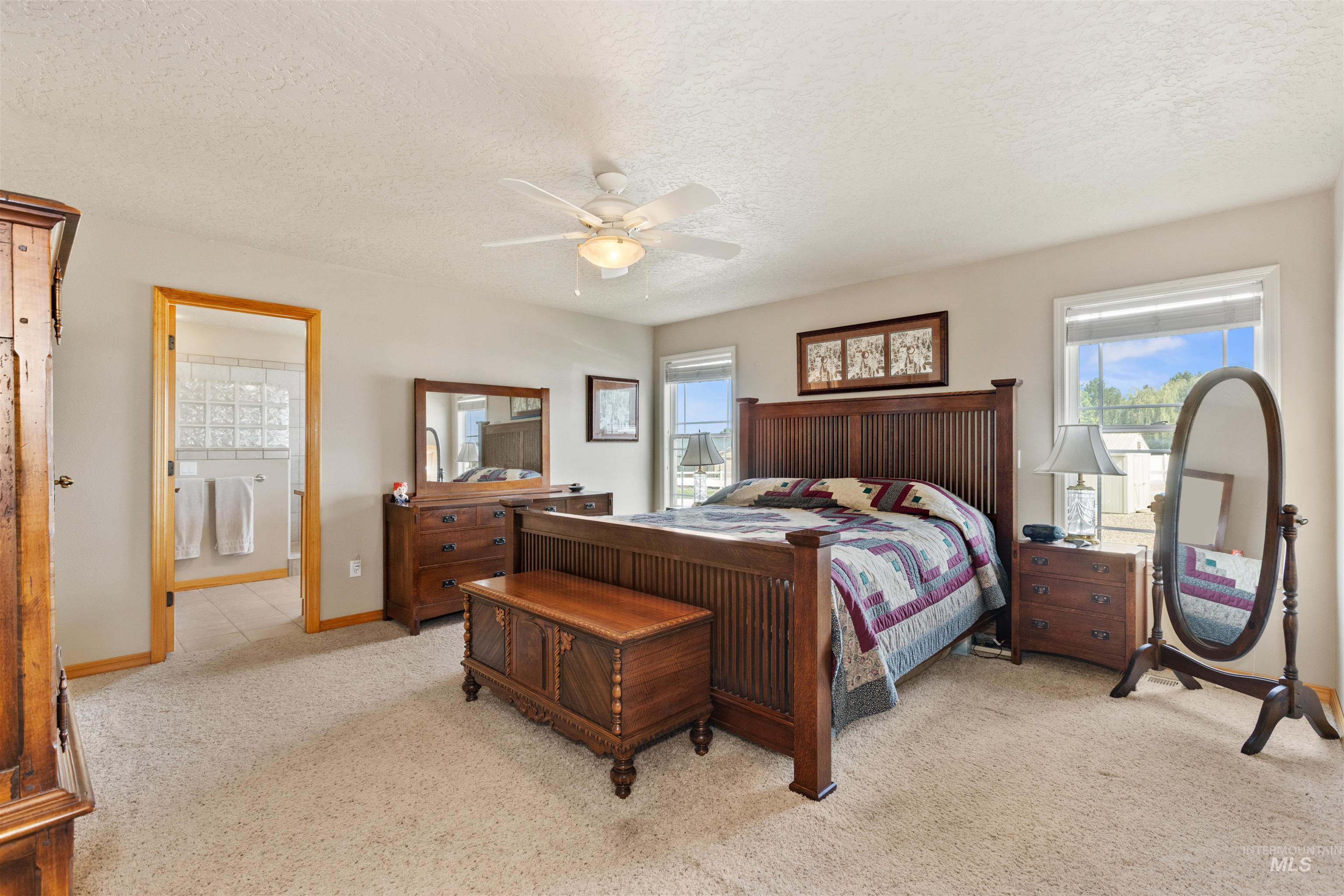 Bedroom featuring a textured ceiling, light carpet, a ceiling fan, and ensuite bathroom