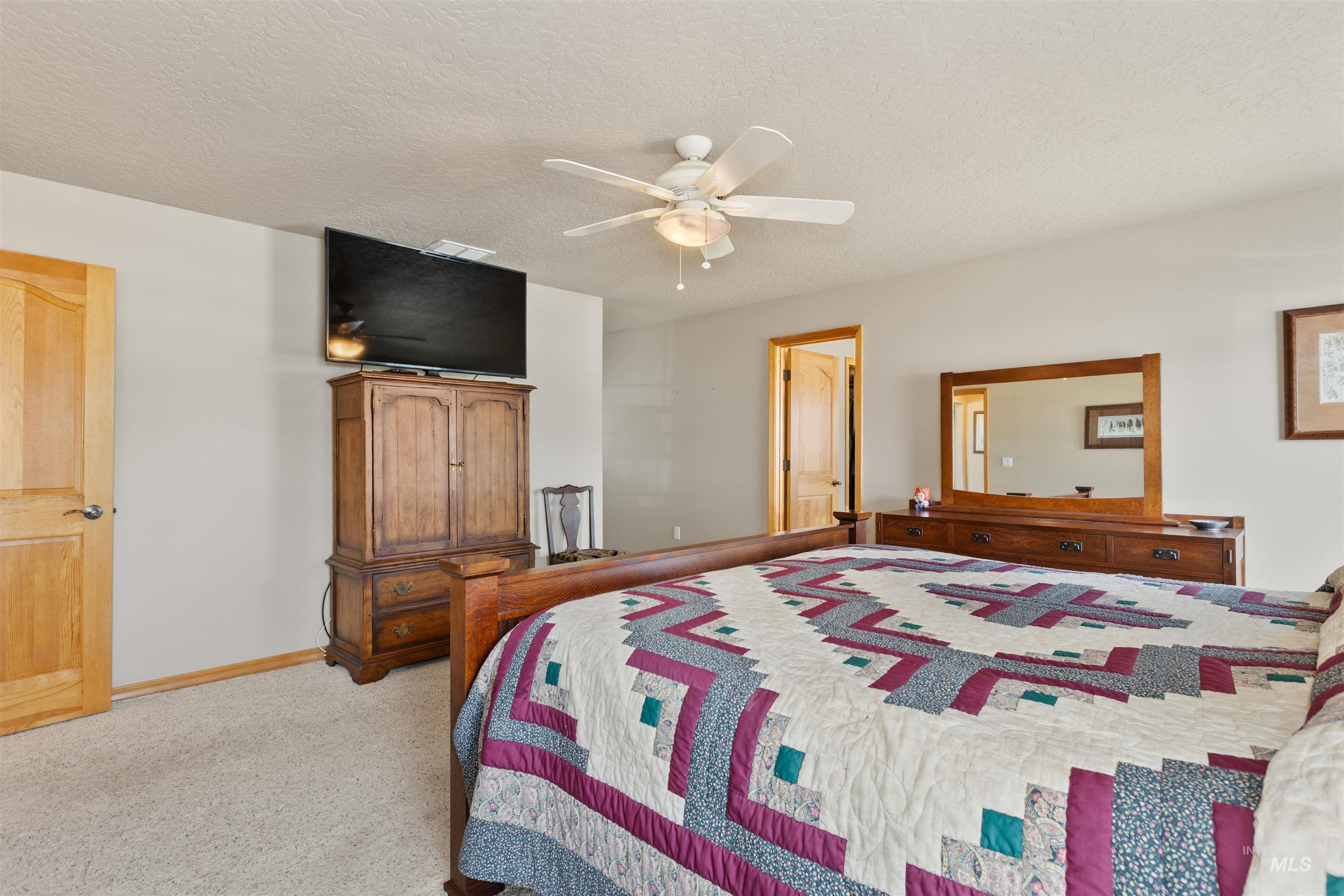 Bedroom with a textured ceiling, ceiling fan, and carpet floors
