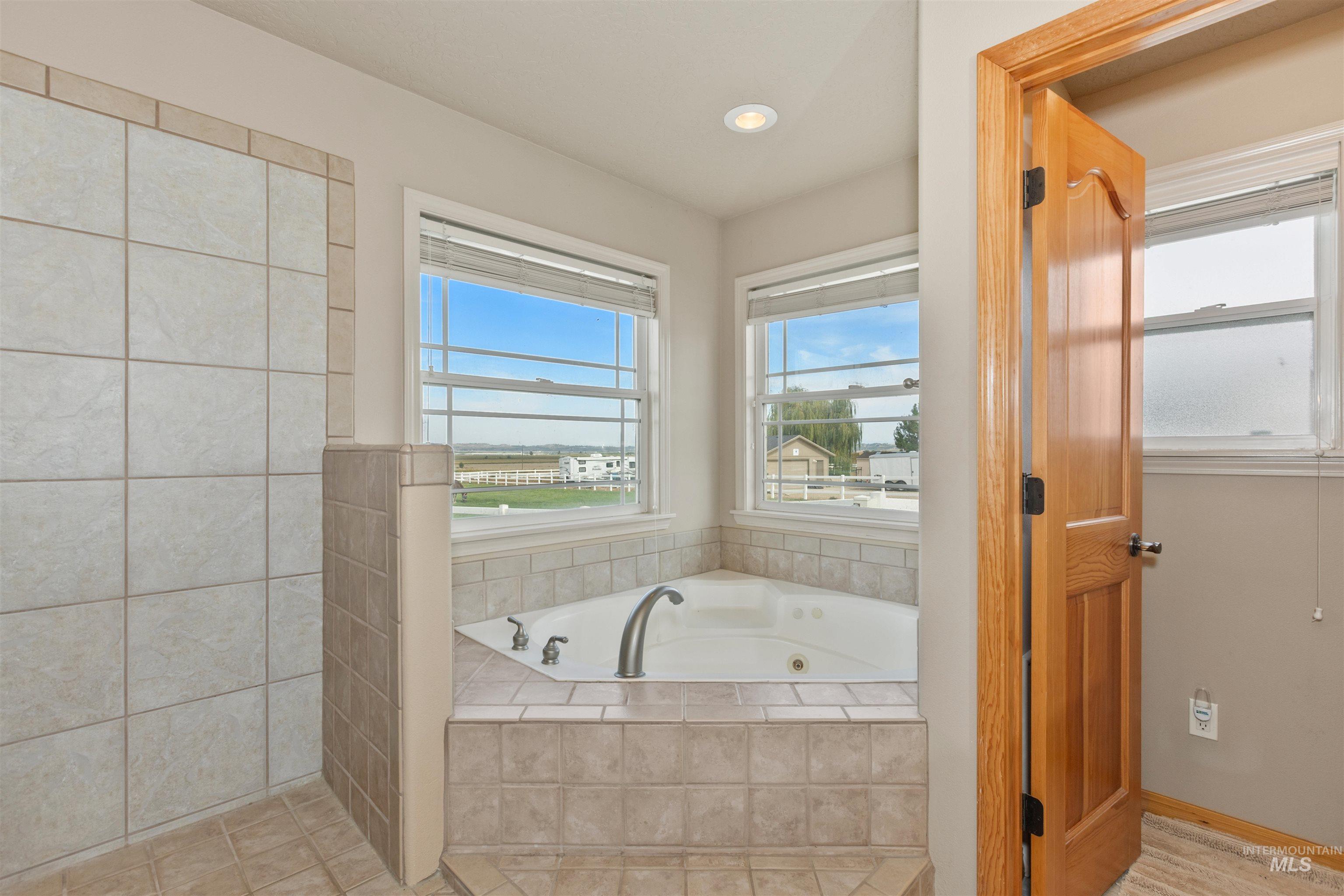 Full bath with a whirlpool tub, recessed lighting, and light tile patterned floors