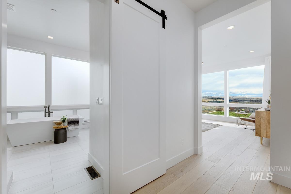 Corridor with a barn door, recessed lighting, and light wood-type flooring