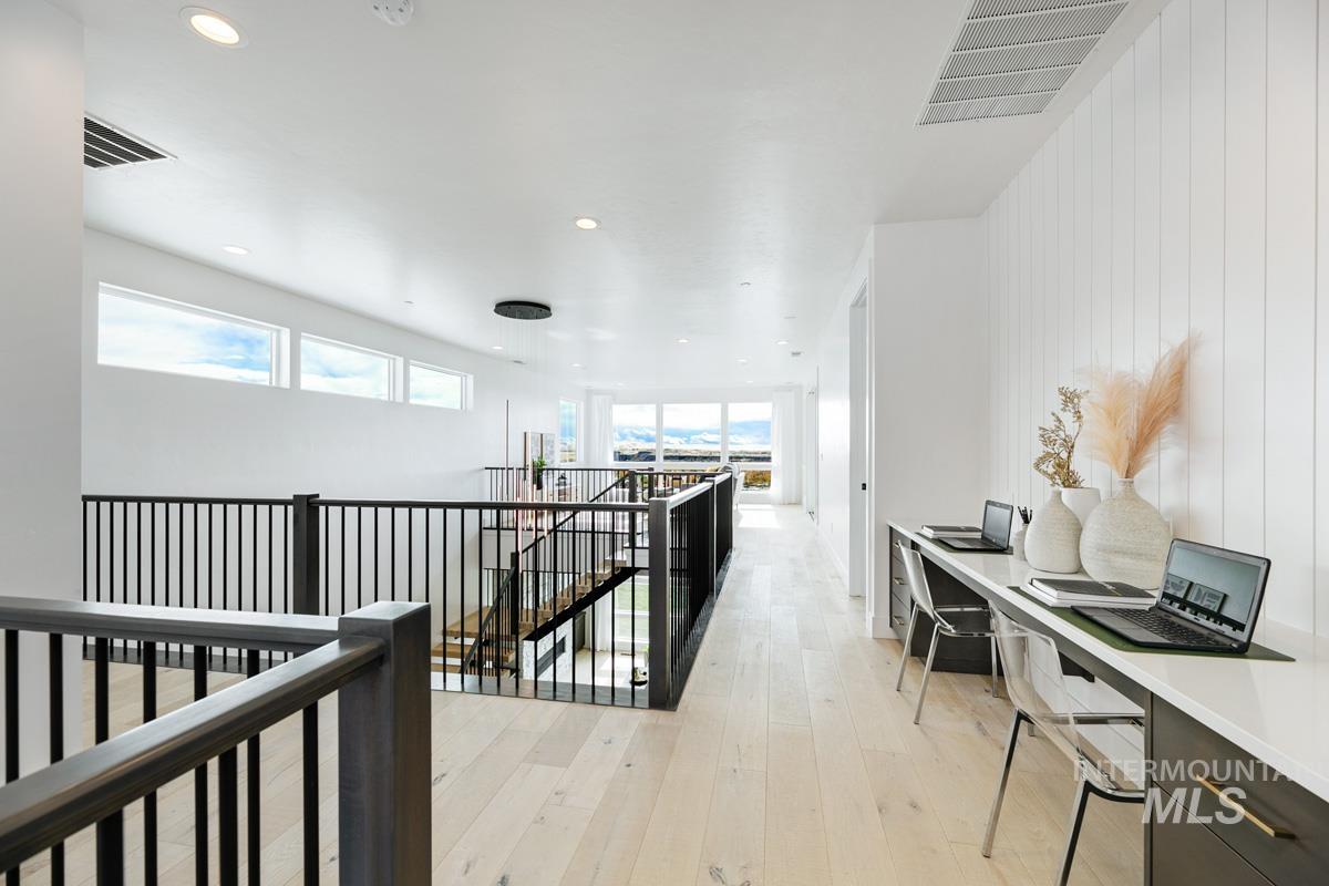 Hallway featuring an upstairs landing, light wood-style flooring, and recessed lighting