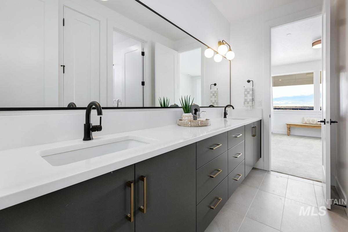Bathroom featuring double vanity, light tile patterned floors, and ensuite bath