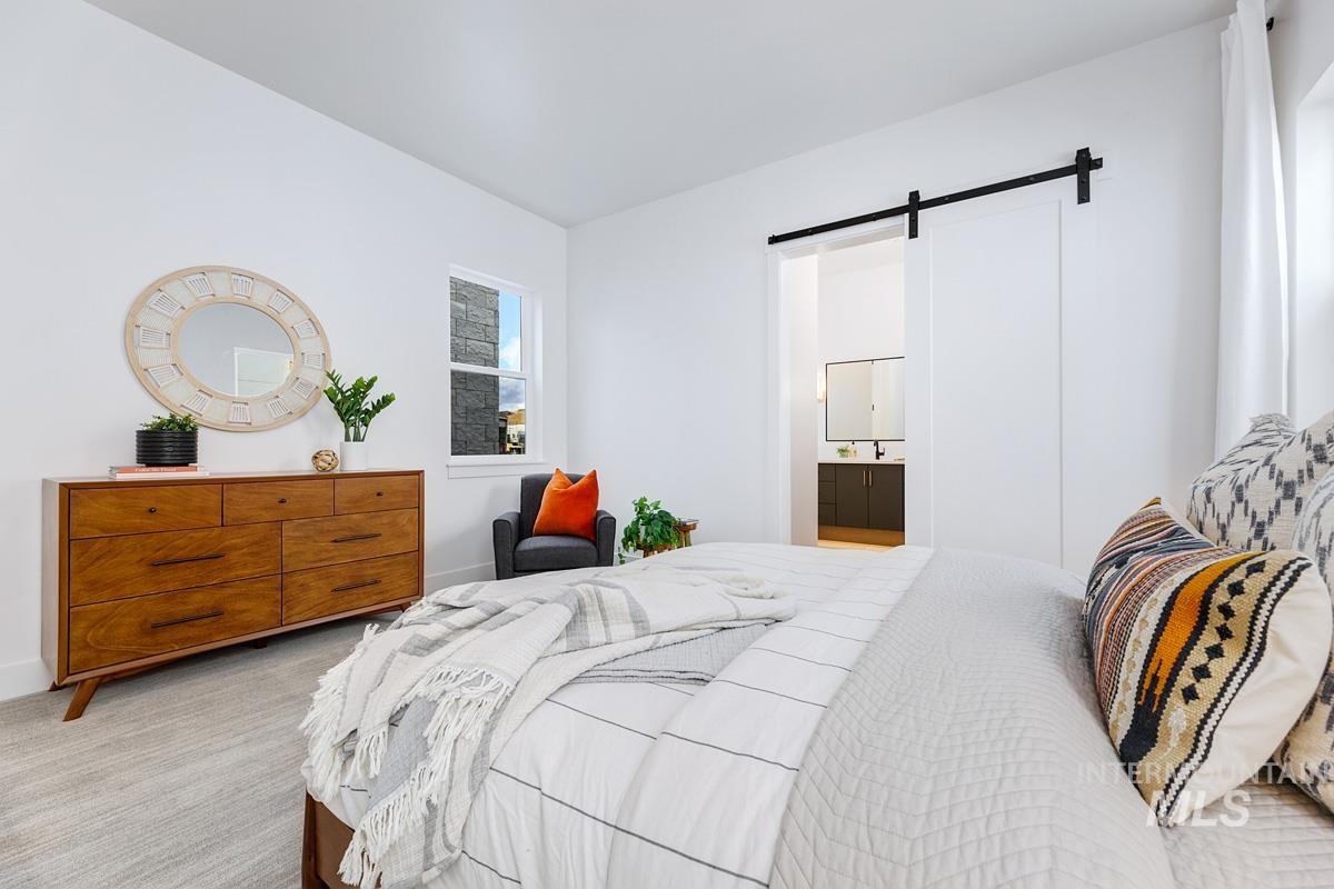 Bedroom featuring a barn door, carpet, and ensuite bathroom