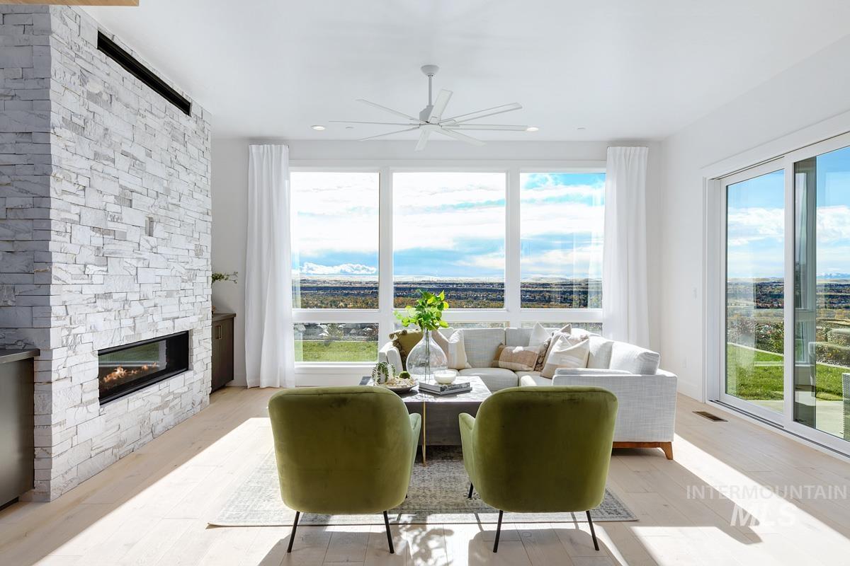 Living room with light wood-type flooring, healthy amount of natural light, a stone fireplace, and a ceiling fan