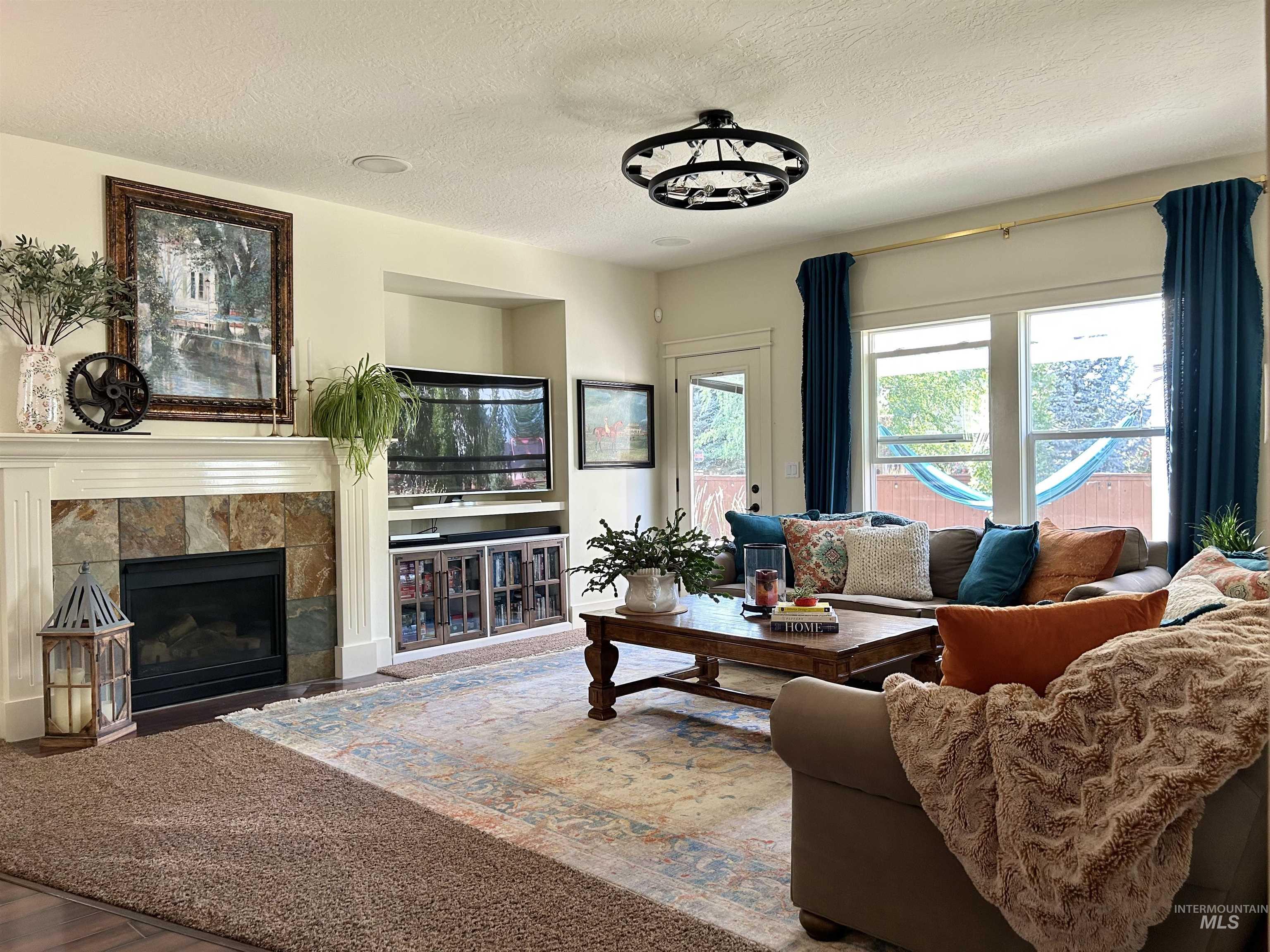 Living area with a tiled fireplace, a textured ceiling, and wood finished floors