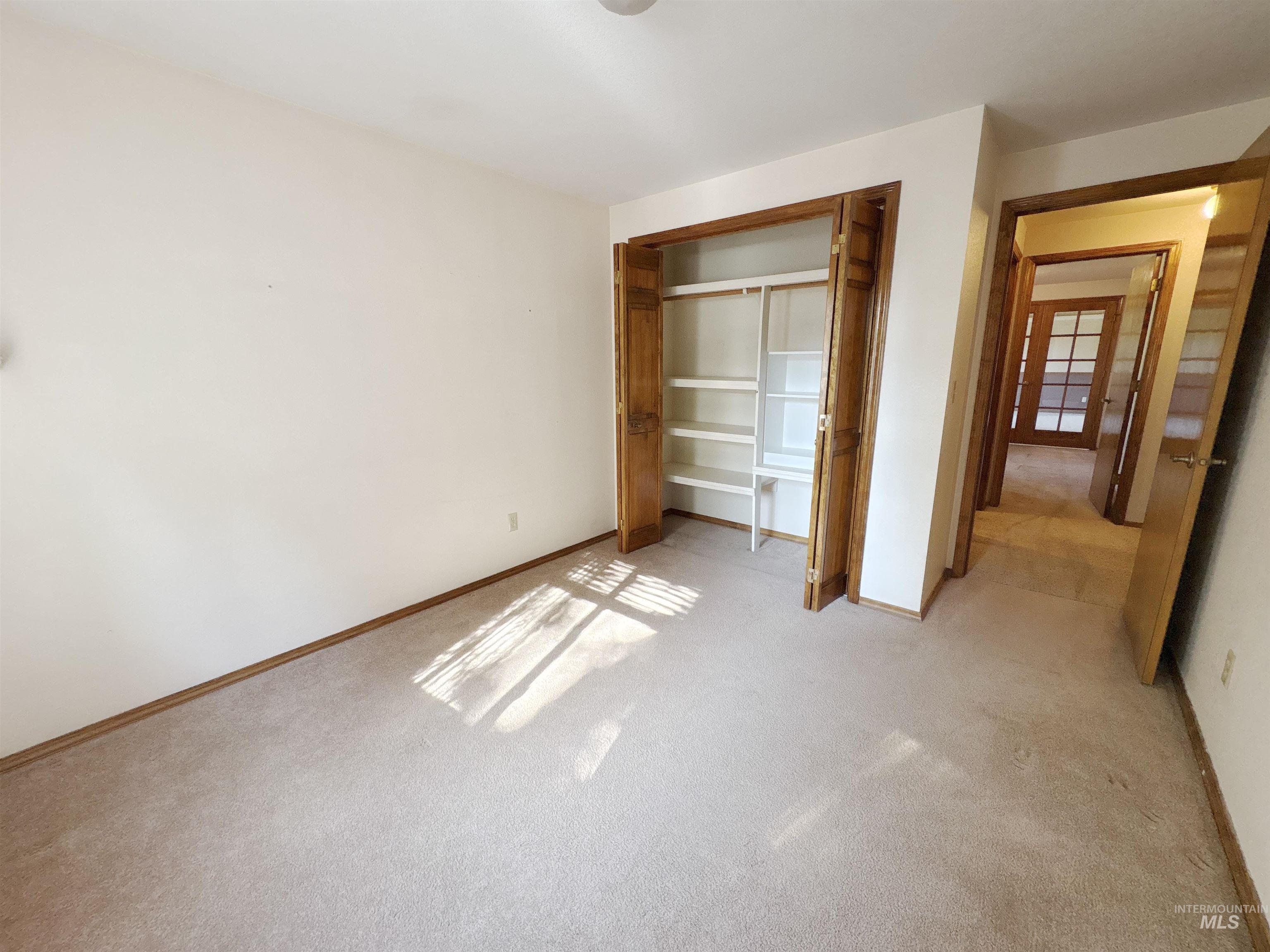 Unfurnished bedroom with light carpet and a closet
