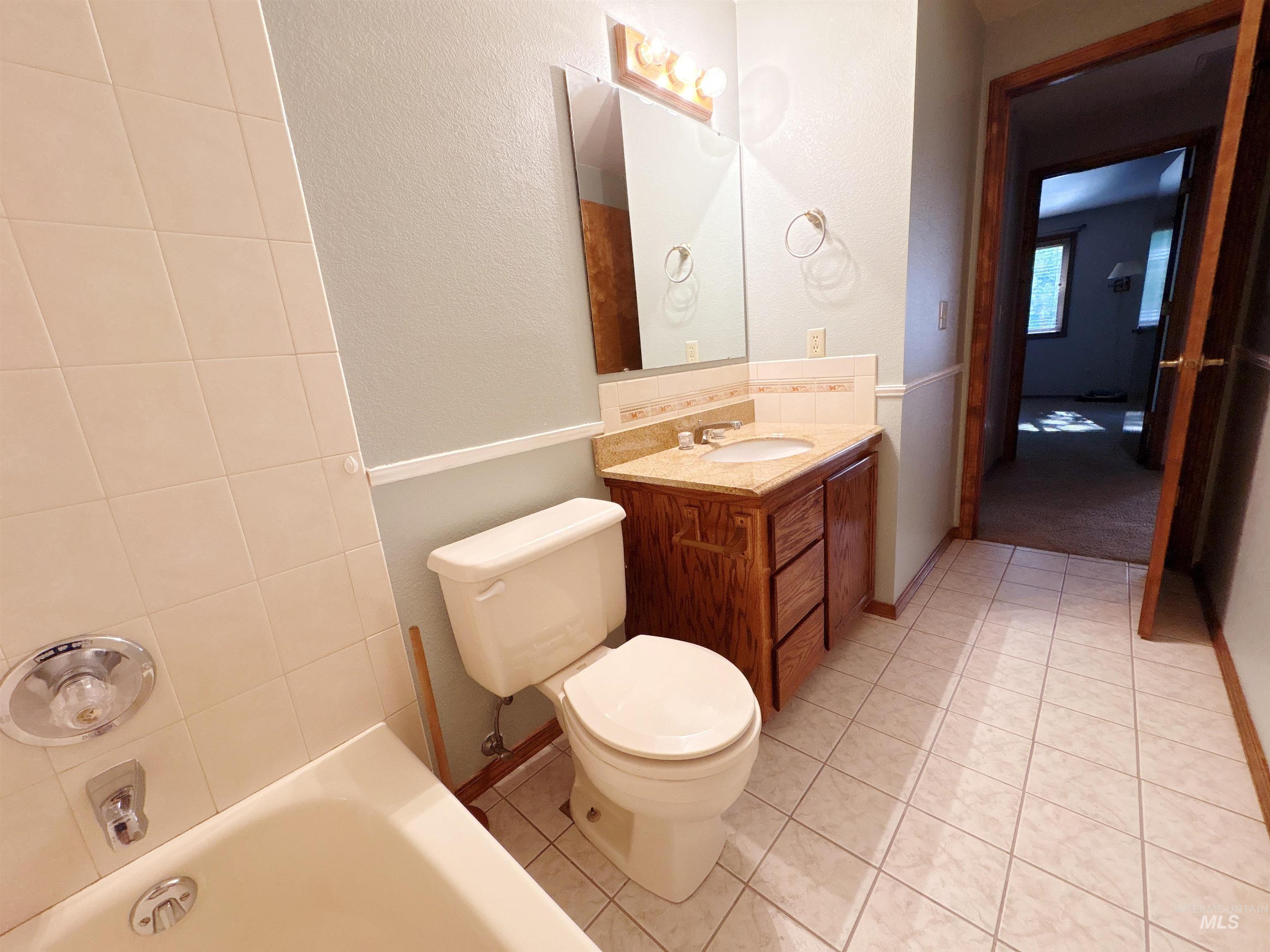 Full bathroom featuring light tile patterned floors, vanity, a textured wall, and bathtub / shower combination
