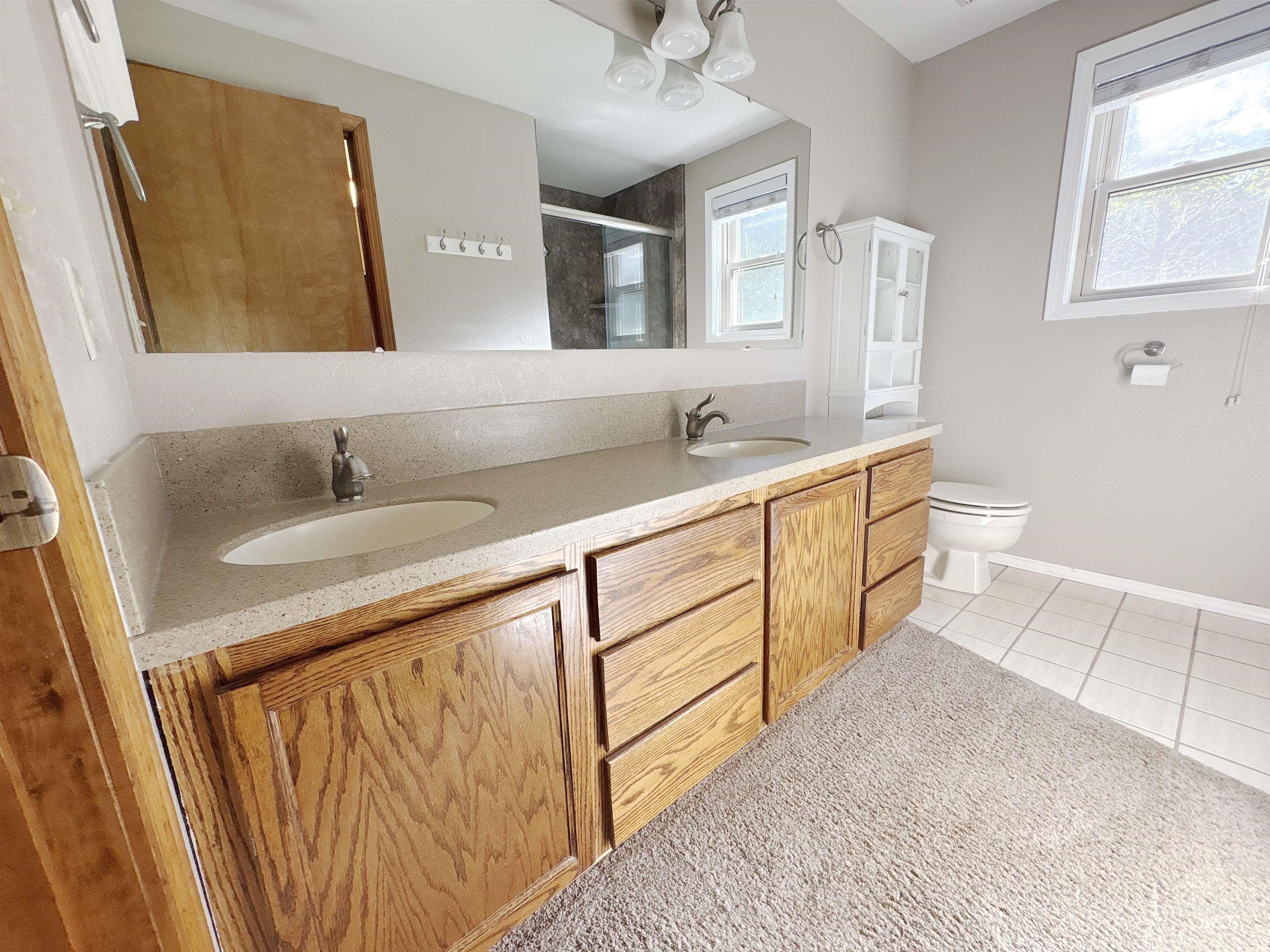 Bathroom featuring a stall shower, double vanity, and light tile patterned flooring