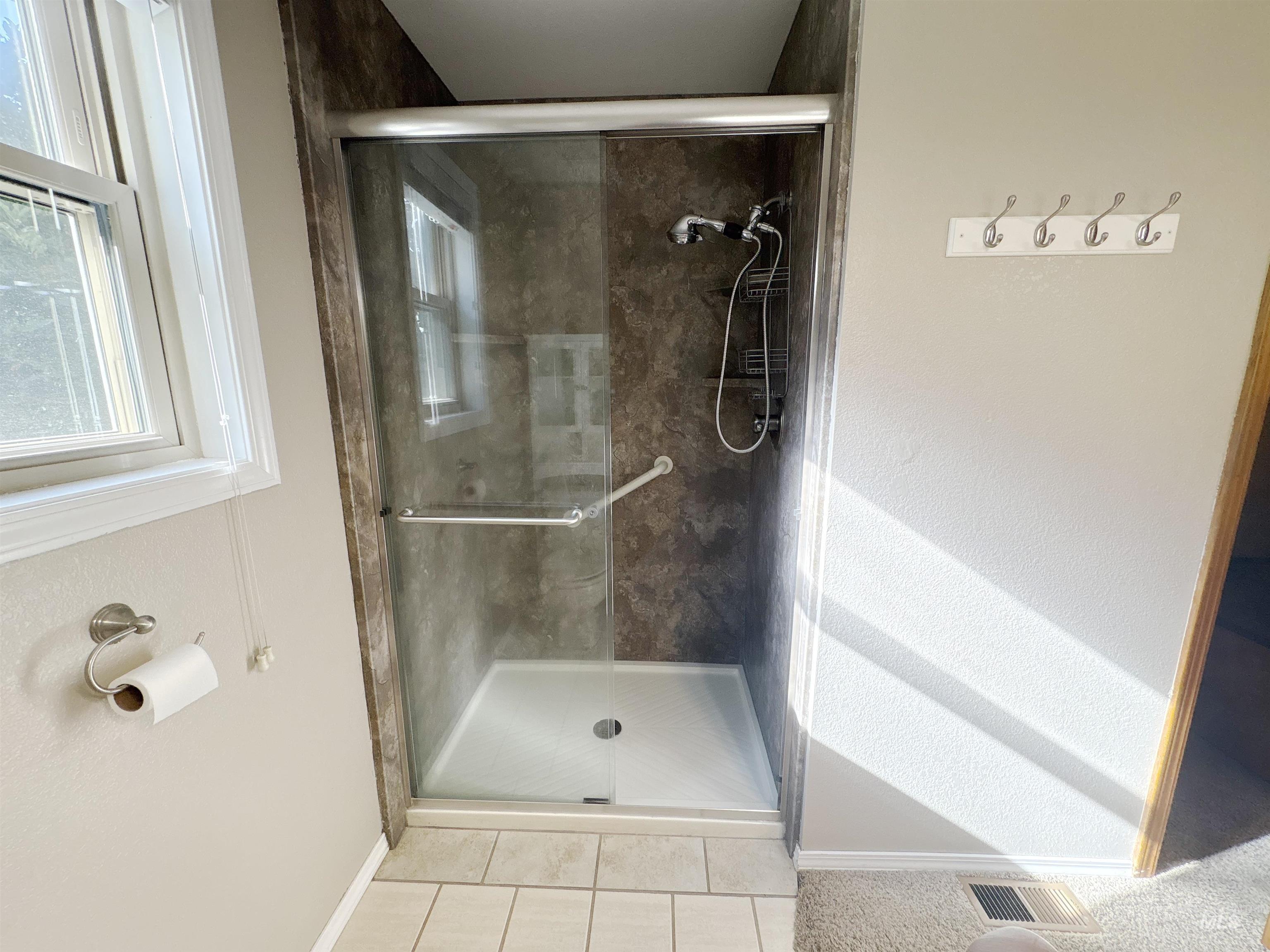 Full bathroom featuring a shower stall and light tile patterned flooring