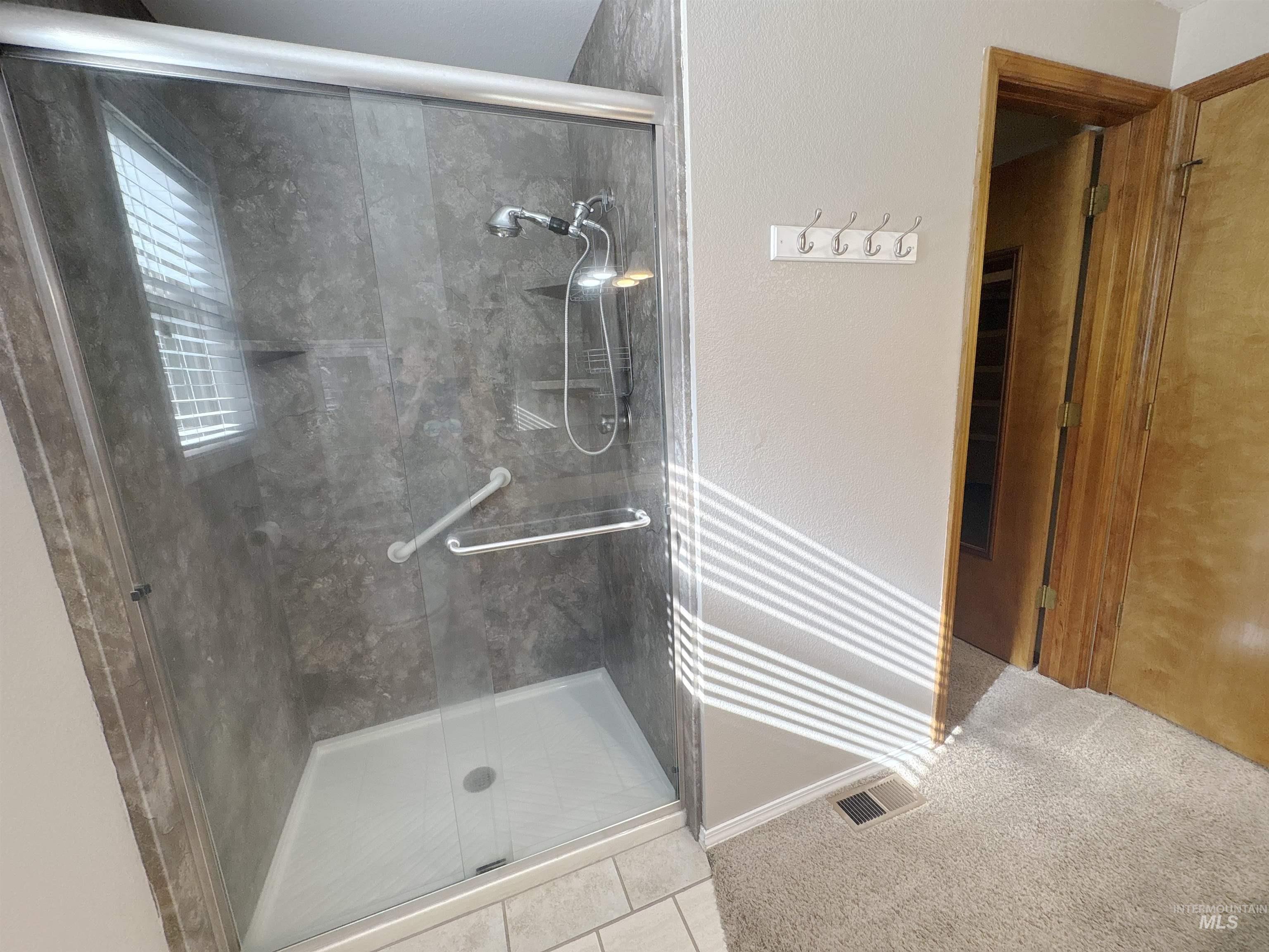 Bathroom with a stall shower, tile patterned flooring, and a textured wall