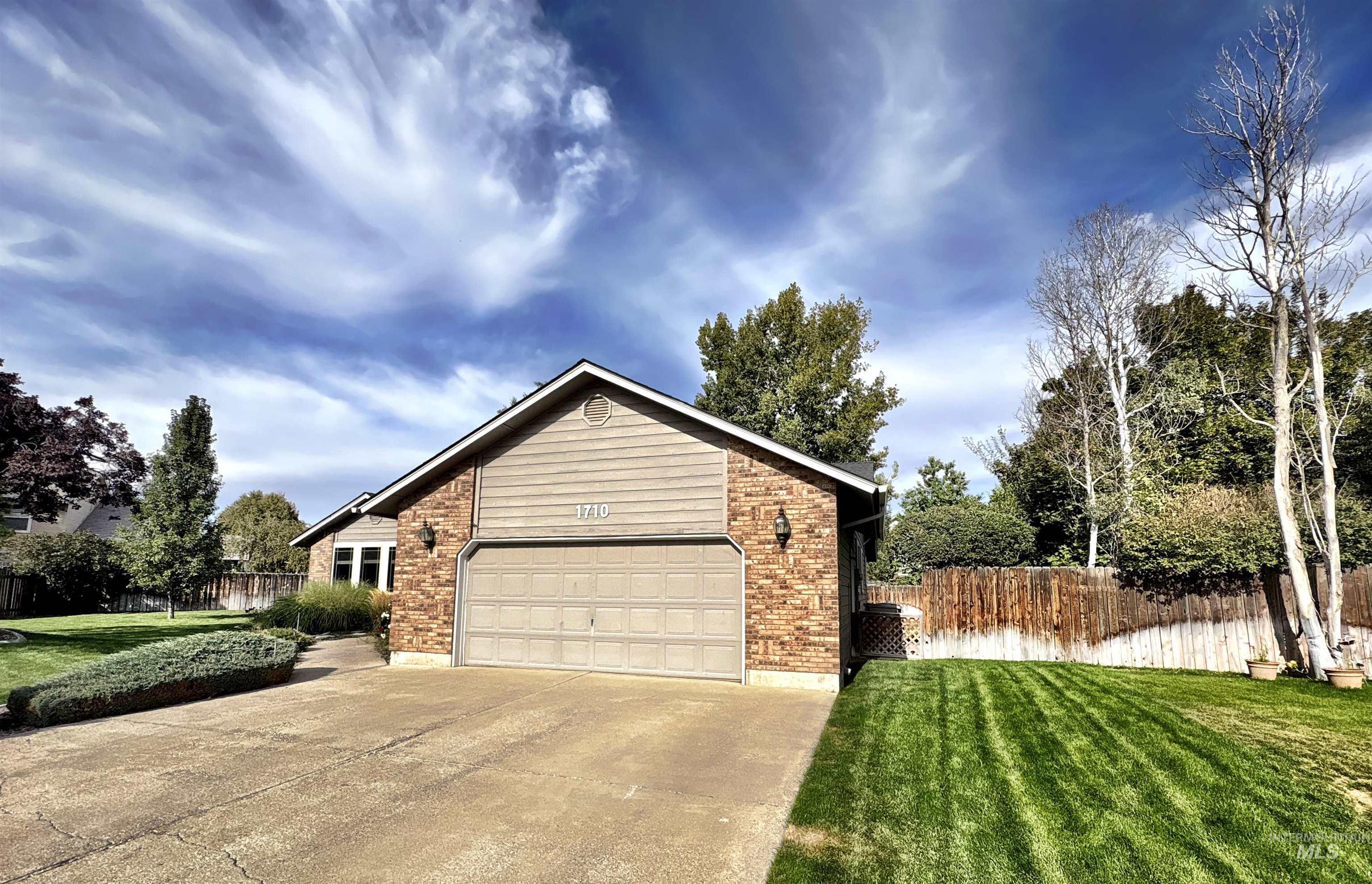 View of side of home with brick siding, driveway, and a garage
