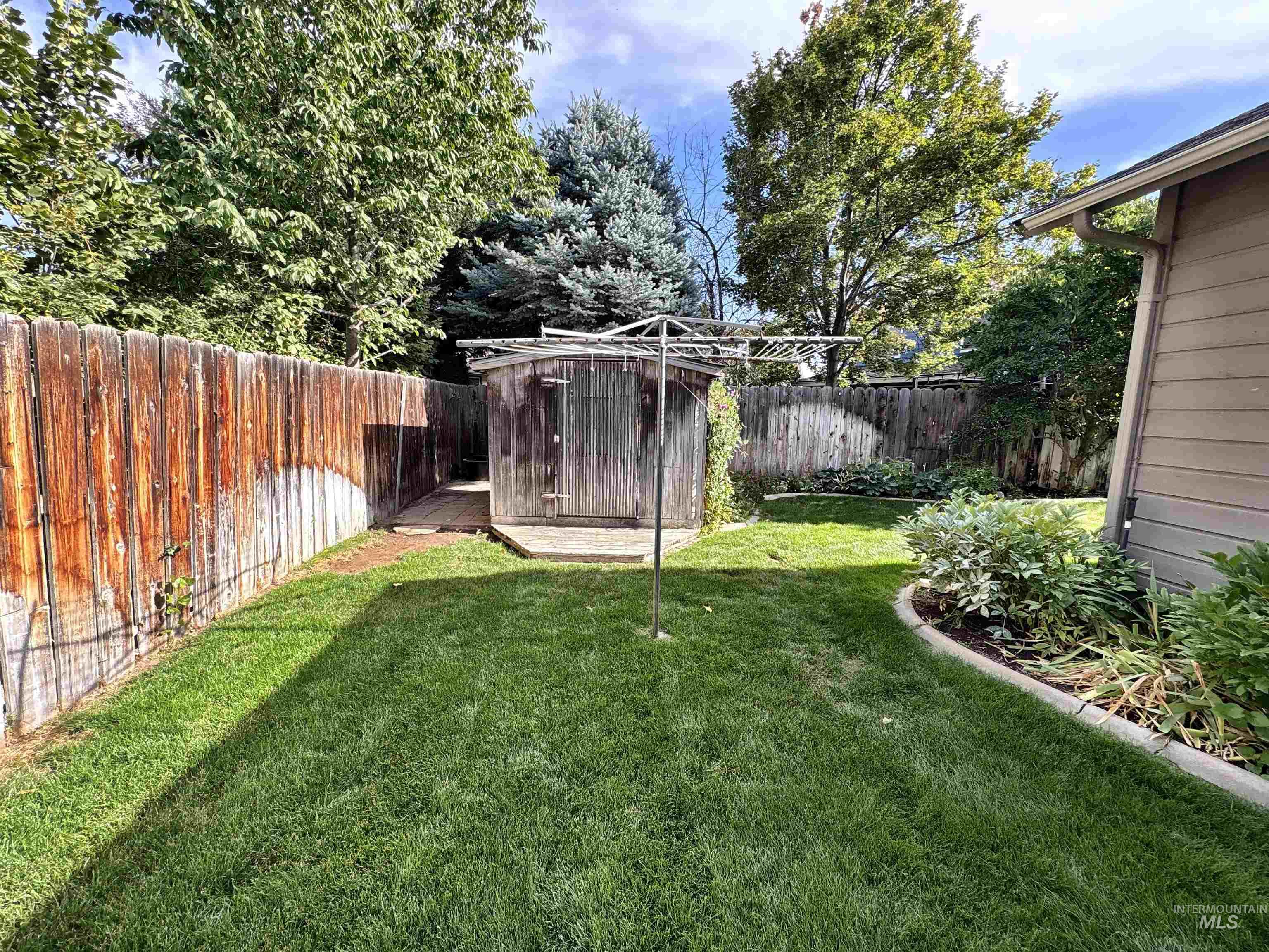 Fenced backyard featuring a storage unit