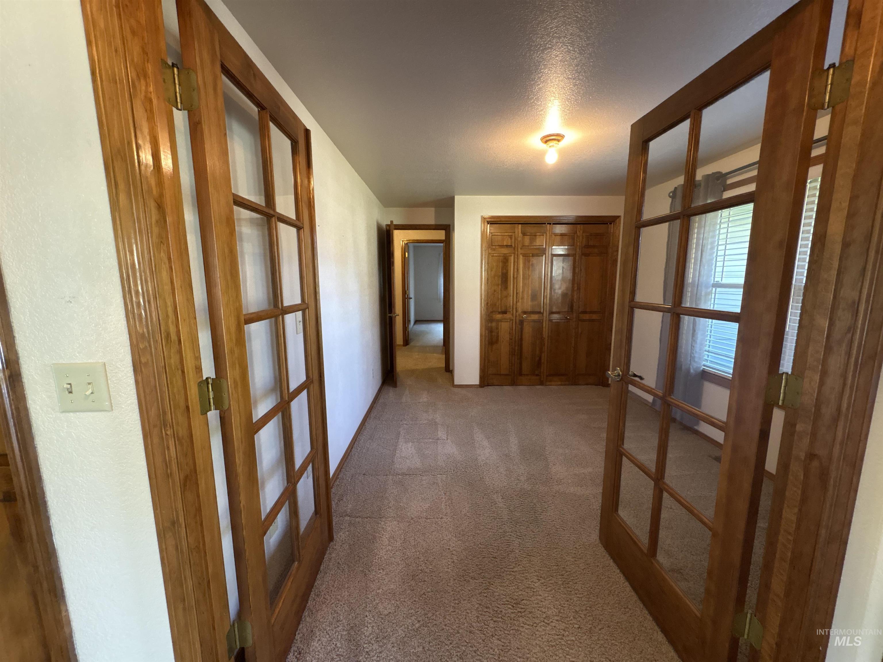 Hall with carpet flooring, french doors, and a textured ceiling
