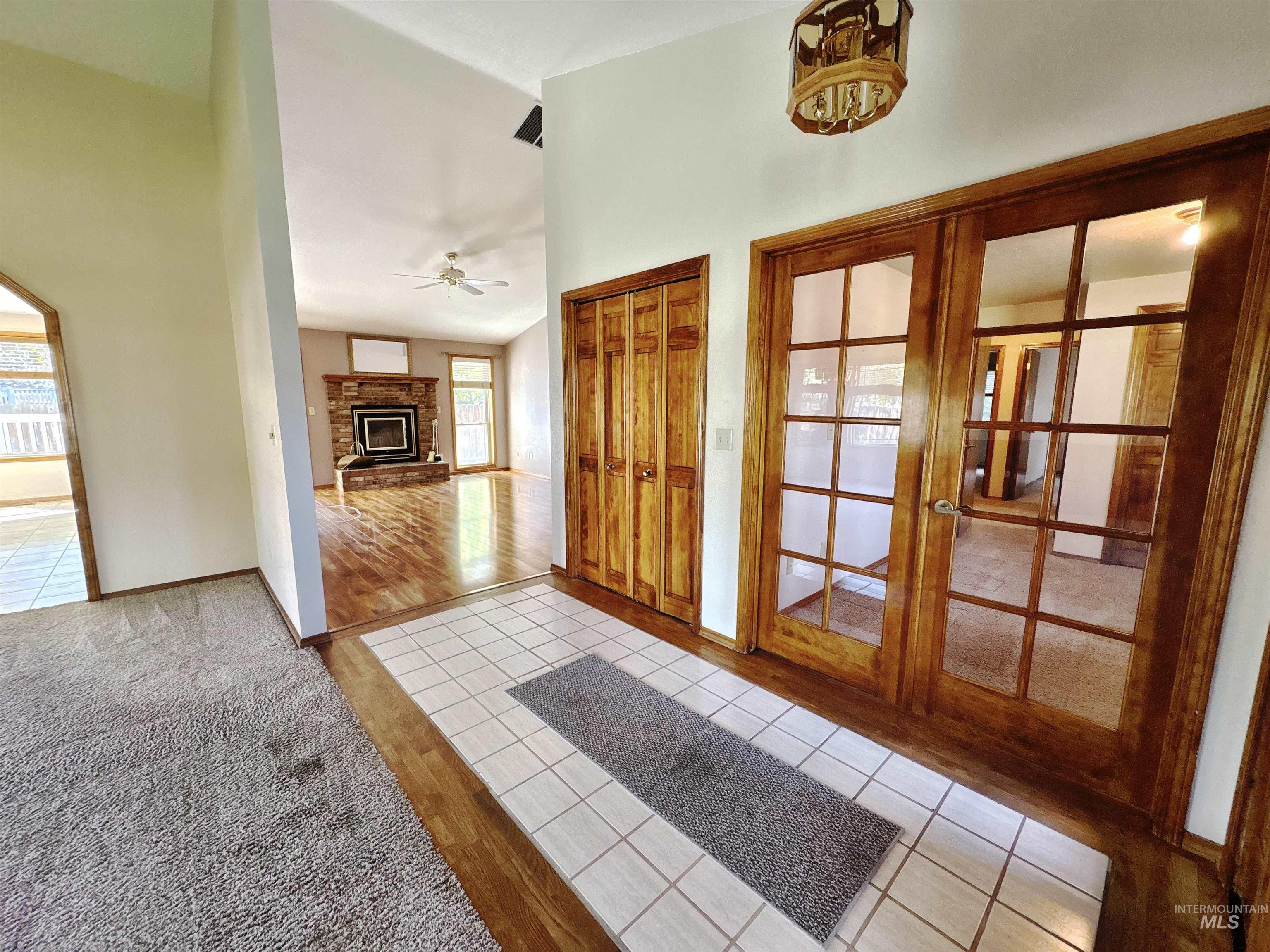 Entryway with light tile patterned floors, french doors, light carpet, a ceiling fan, and a glass covered fireplace
