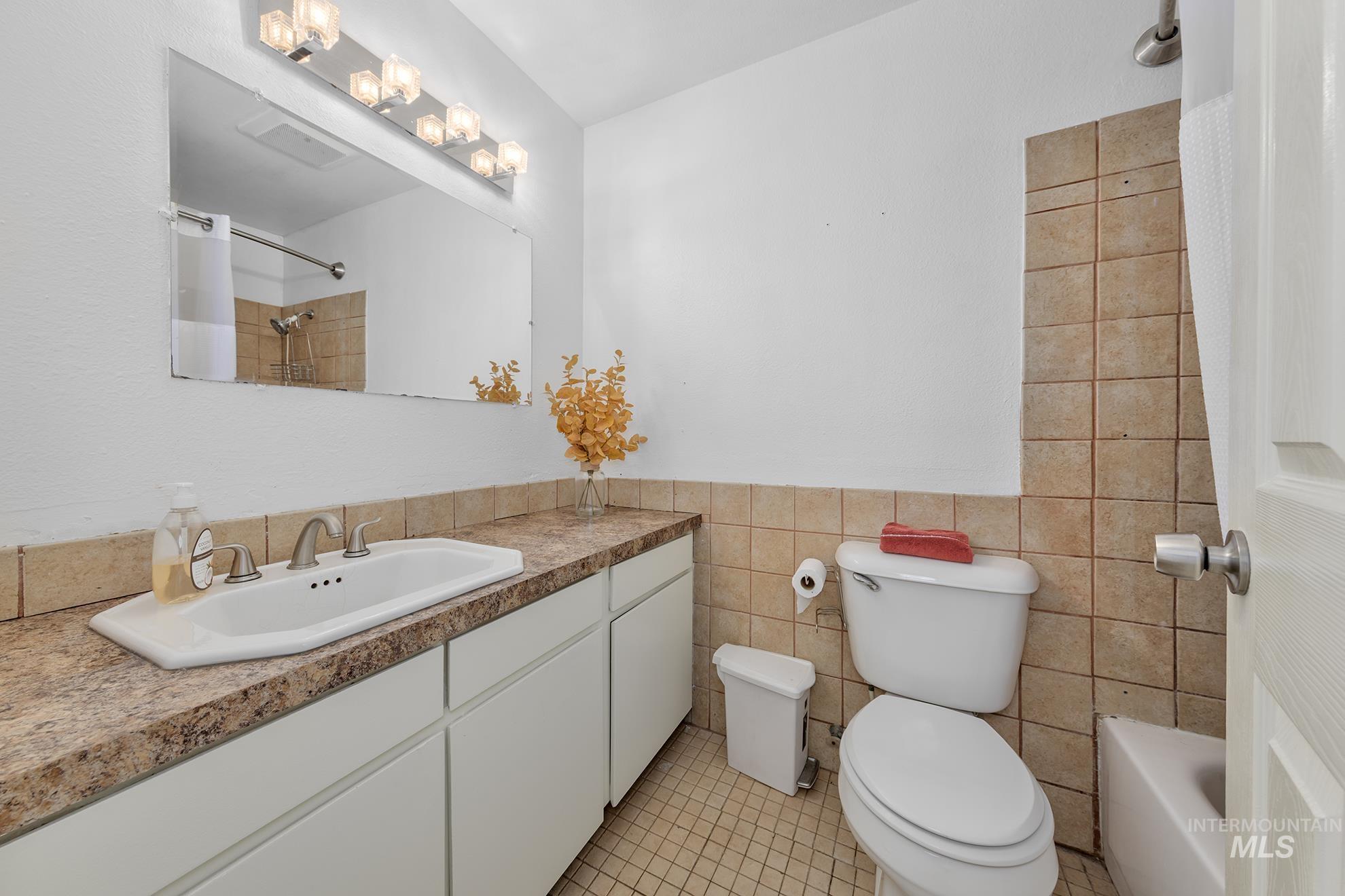 Bathroom with vanity, light tile patterned floors, shower / bath combo, and tile walls