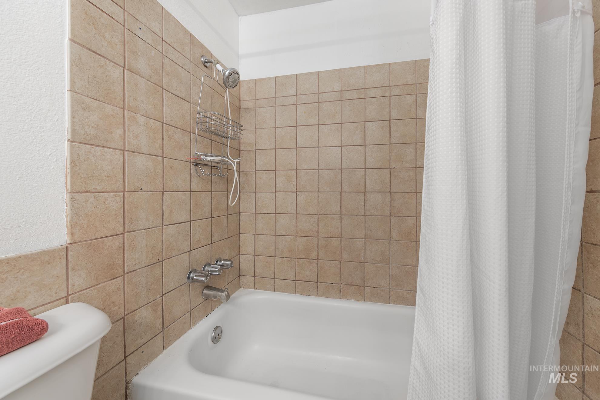 Full bath with shower / tub combo with curtain and tile walls