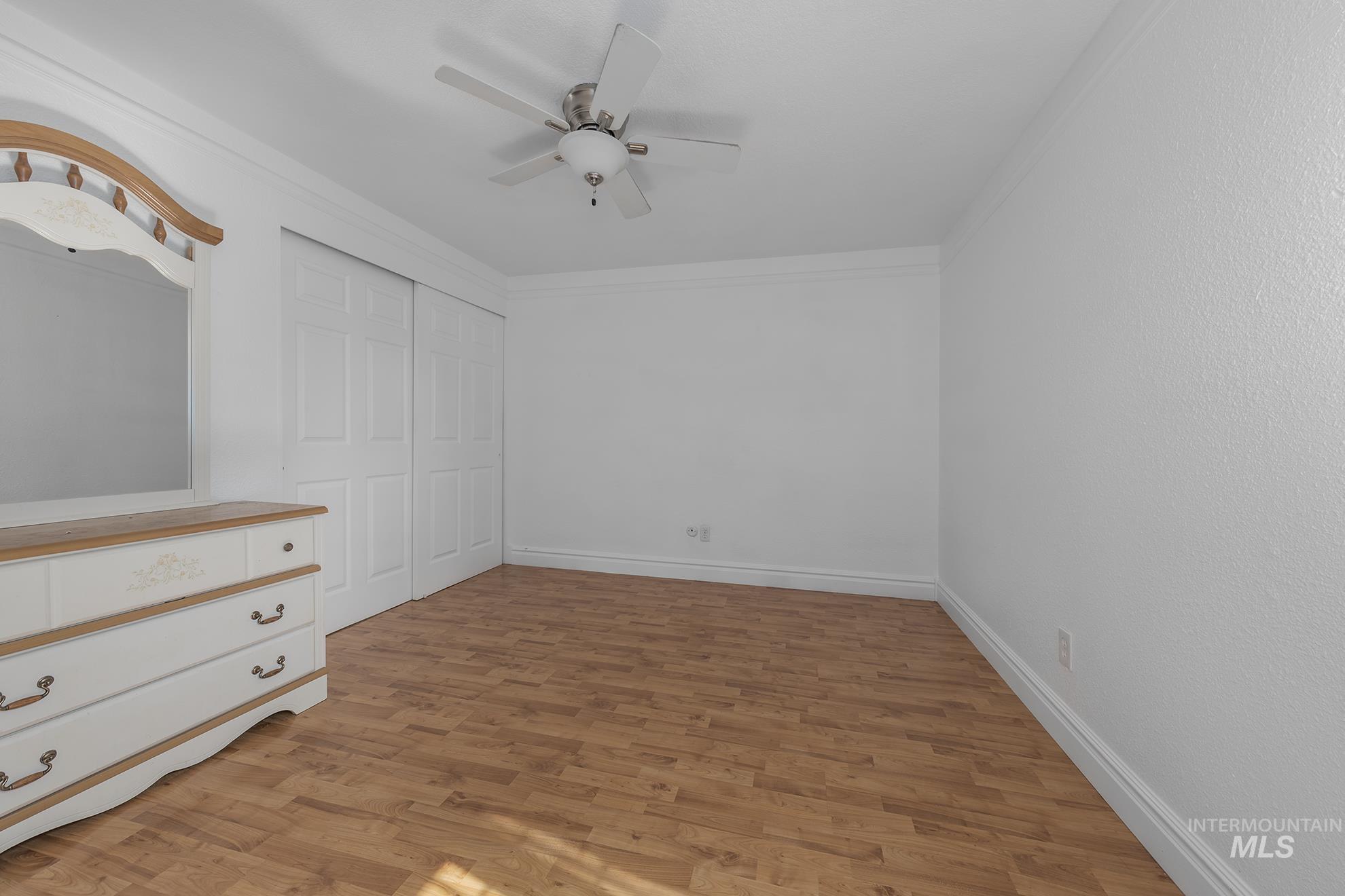Unfurnished bedroom with light wood-type flooring, a ceiling fan, a closet, and ornamental molding